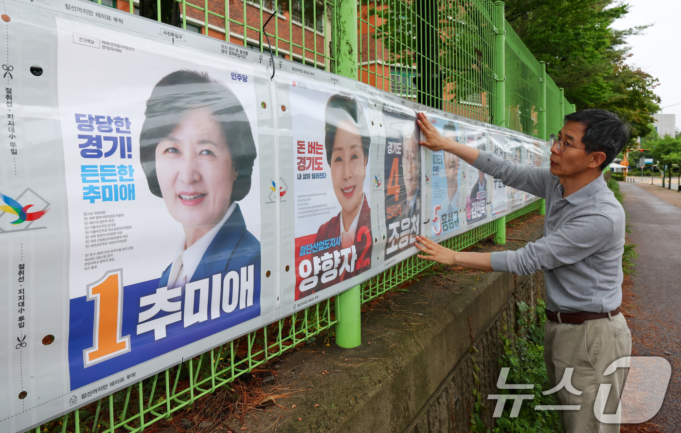 (수원=뉴스1) 안은나 기자 = 경기도선거관리위원회 관계자들이 제9회 전국동시지방선거 공식 선거운동이 시작된 21일 경기 수원시 팔달구 율현중학교 펜스에 경기도지사, 수원시장, 도 …