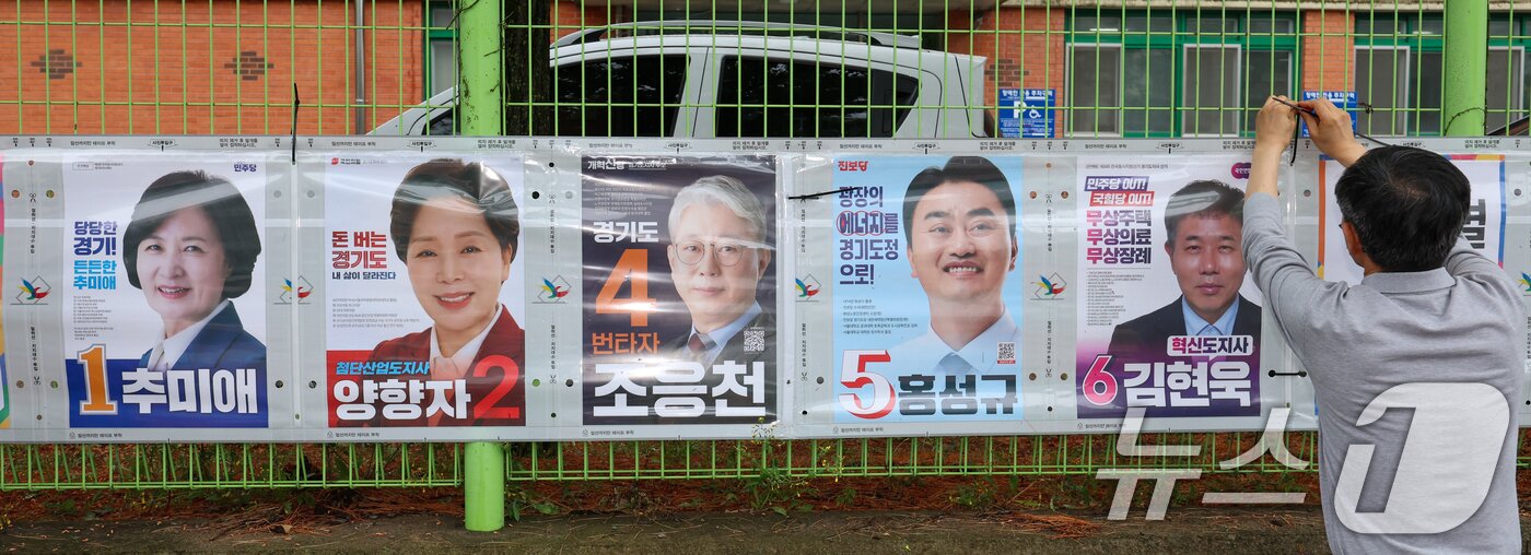 본문 이미지 - 경기도선거관리위원회 직원들이 제9회 전국동시지방선거 공식 선거운동이 시작된 21일 경기 수원시 팔달구 율현중학교 펜스에 경기도지사 후보 선거벽보를 첩부하고 있다. 2026.5.21 ⓒ 뉴스1 안은나 기자