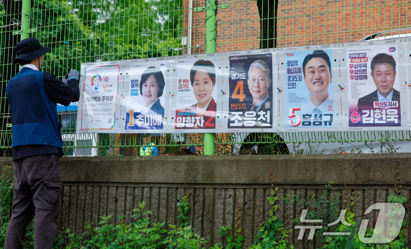 본문 이미지 - 경기도선거관리위원회 관계자들이 제9회 전국동시지방선거 공식 선거운동이 시작된 21일 경기 수원시 팔달구 율현중학교 펜스에 경기도지사 후보 선거벽보를 첩부하고 있다. 2026.5.21 ⓒ 뉴스1 안은나 기자