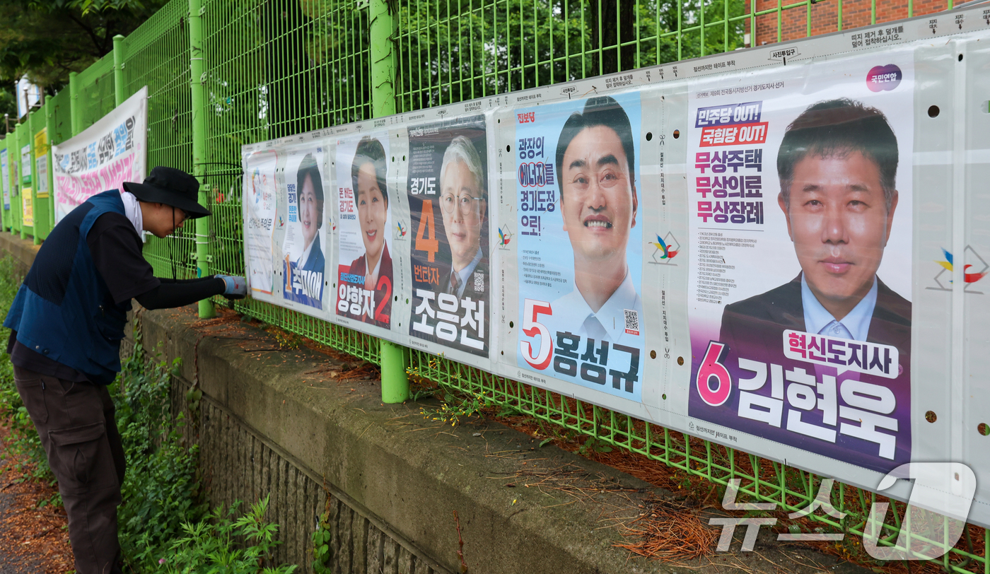 (수원=뉴스1) 안은나 기자 = 경기도선거관리위원회 직원들이 제9회 전국동시지방선거 공식 선거운동이 시작된 21일 경기 수원시 팔달구 율현중학교 펜스에 경기도지사, 수원시장, 도의 …