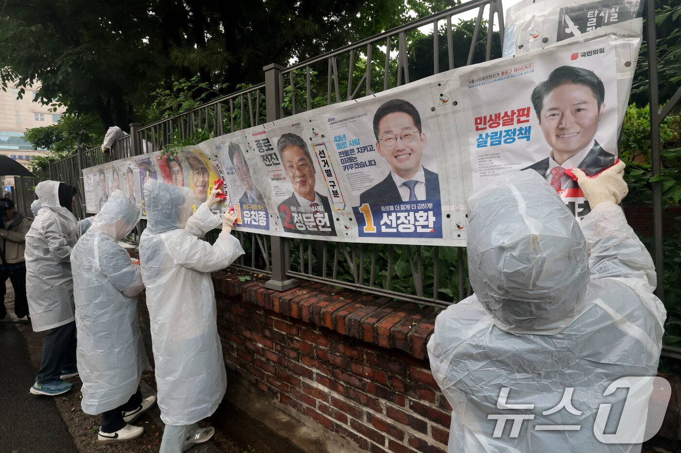 본문 이미지 - 제9회 전국동시지방선거 공식 선거운동이 시작된 21일 오전 서울 종로구 예술가의 집 담장에 서울시선관위 직원들이 선거벽보를 첩부하고 있다. 2026.5.21 ⓒ 뉴스1 이광호 기자