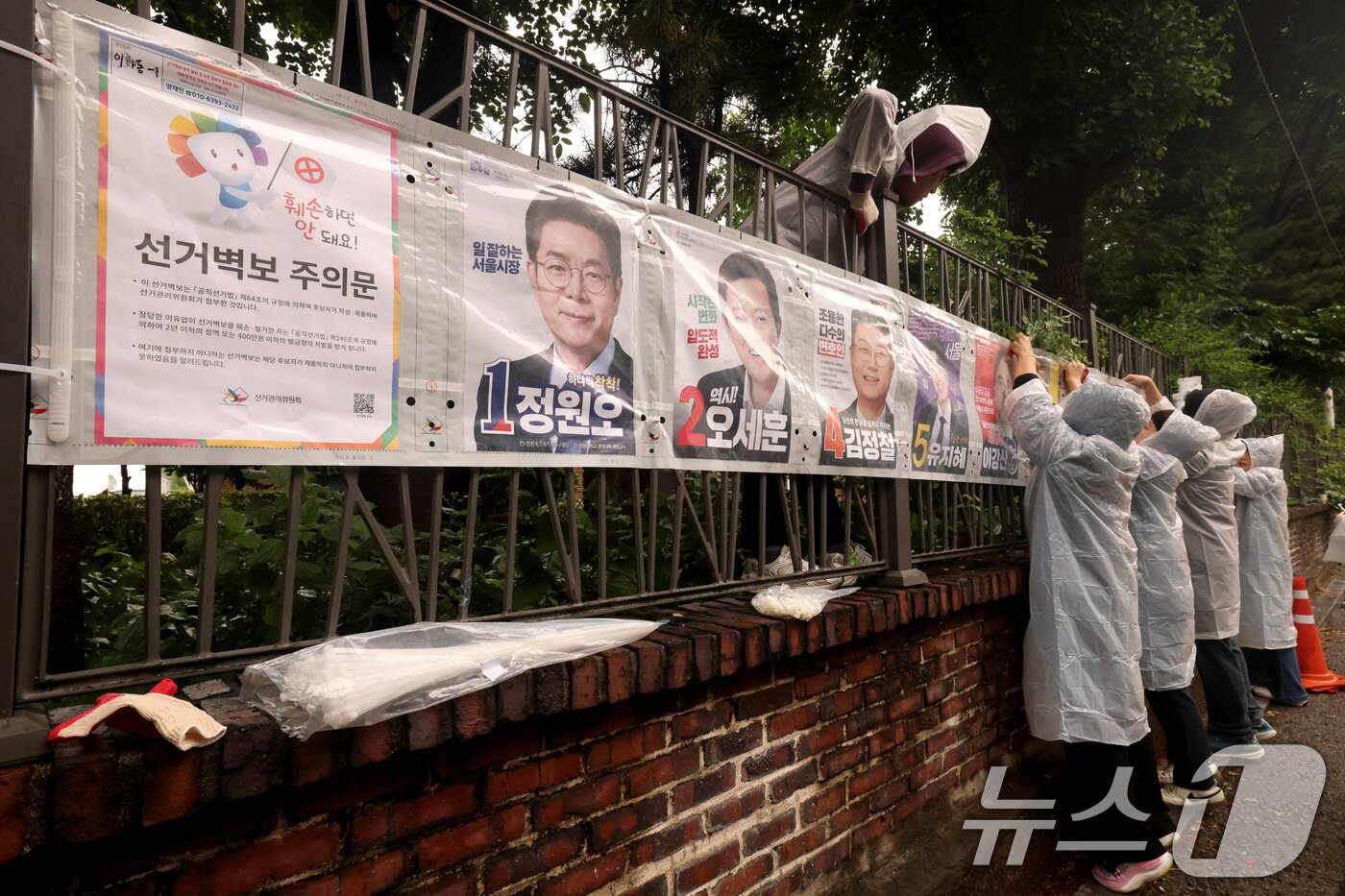 본문 이미지 - 제9회 전국동시지방선거 공식 선거운동이 시작된 21일 오전 서울 종로구 예술가의 집 담장에 서울시선관위 직원들이 선거벽보를 첩부하고 있다. 2026.5.21 ⓒ 뉴스1 이광호 기자
