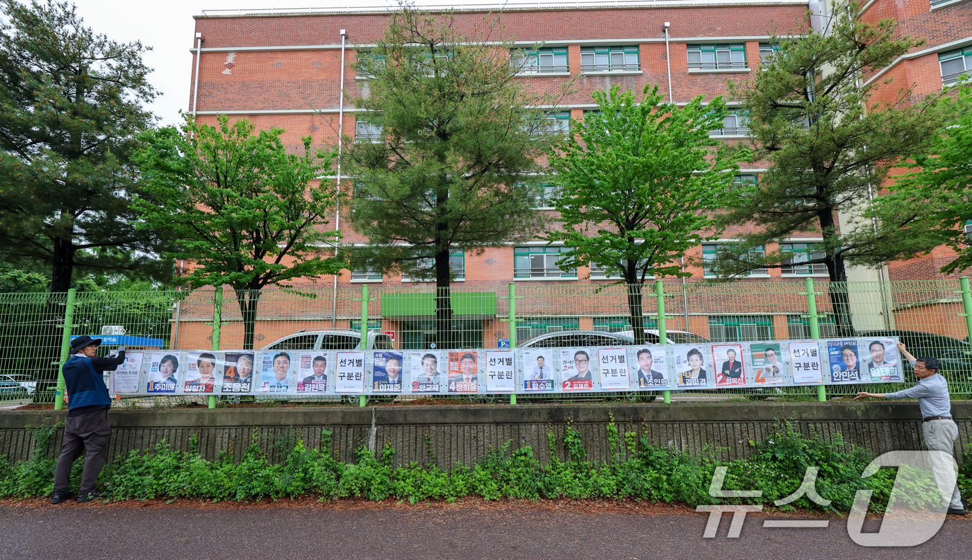 (수원=뉴스1) 안은나 기자 = 경기도선거관리위원회 직원들이 제9회 전국동시지방선거 공식 선거운동이 시작된 21일 경기 수원시 팔달구 율현중학교 펜스에 경기도지사, 수원시장, 도의 …