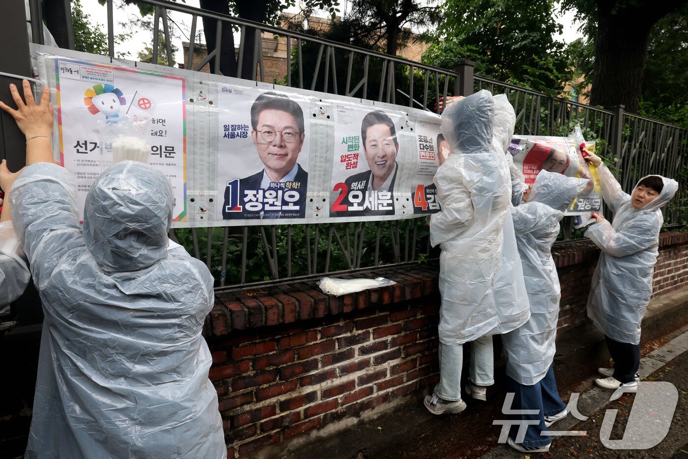 본문 이미지 - 제9회 전국동시지방선거 공식 선거운동이 시작된 21일 오전 서울 종로구 예술가의 집 담장에 서울시선관위 직원들이 선거벽보를 첩부하고 있다. 2026.5.21 ⓒ 뉴스1 이광호 기자