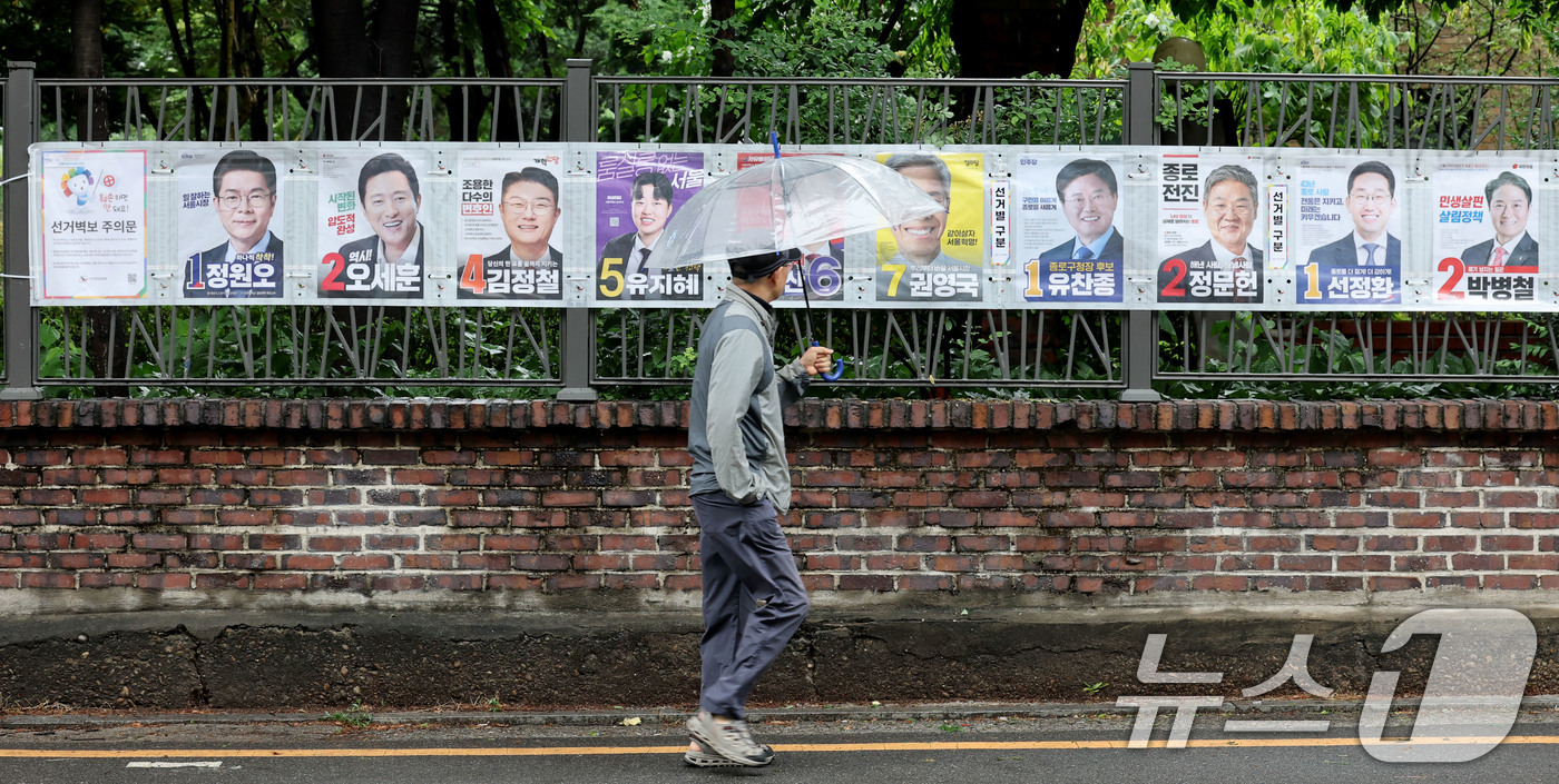 (서울=뉴스1) 이광호 기자 = 제9회 전국동시지방선거 공식 선거운동이 시작된 21일 오전 한 시민이 서울 종로구 예술가의 집 담장에 걸린 선거벽보를 살펴보고 있다.  2026.5 …