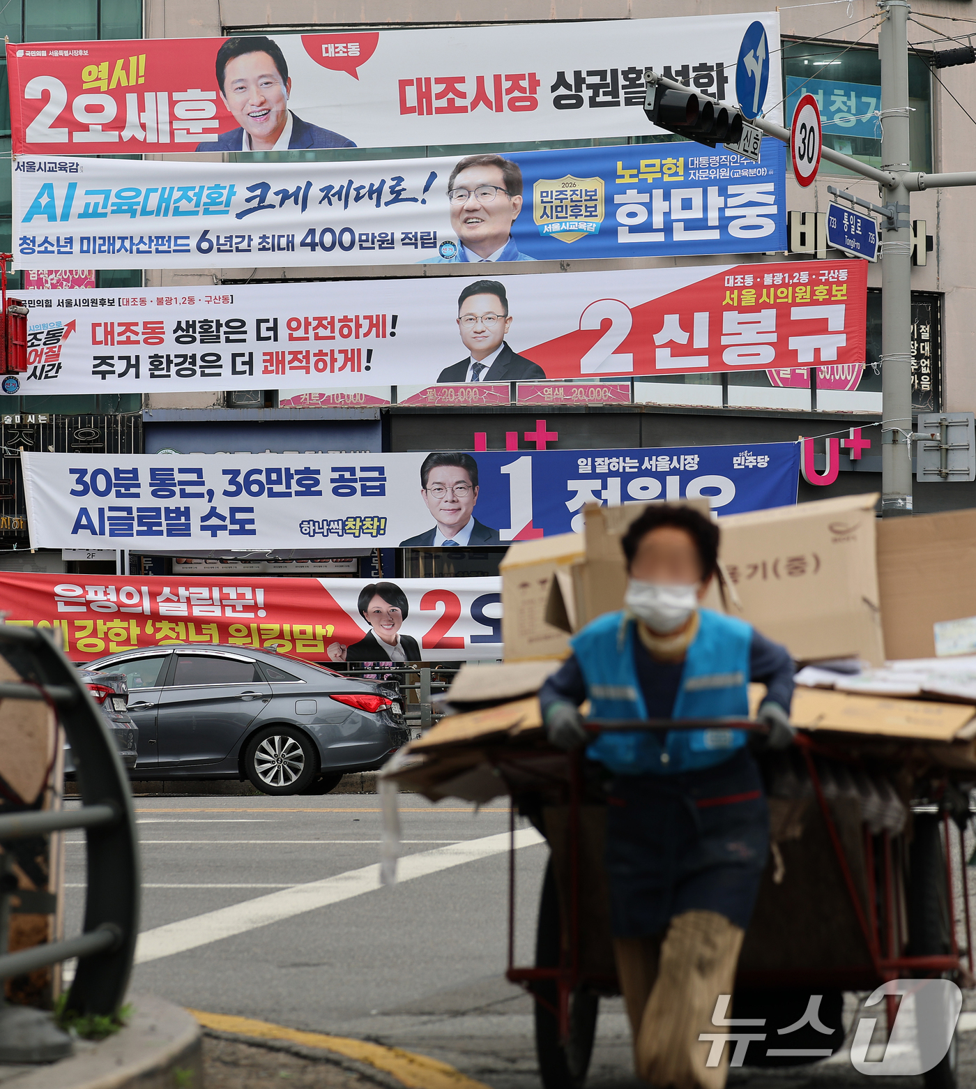 (서울=뉴스1) 오대일 기자 = 6·3 지방선거 공식 선거운동이 시작된 21일 서울 은평구의 한 거리에서 폐지 수레를 끄는 할머니가 여야 후보자들의 선거 현수막 앞을 힘겹게 지나고 …