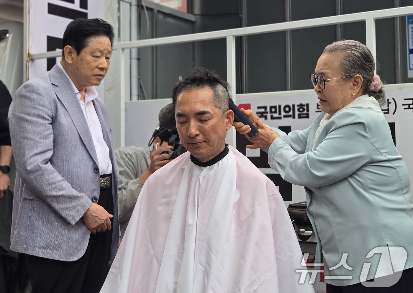 본문 이미지 - 박민식 국민의힘 부산 북구갑 국회의원 후보가 6·3 지방선거 및 국회의원 재보궐선거 공식 선거운동 첫날인 21일 오후 부산 북구 구포시장 인근 쌈지공원에서 열린 출정식에서 삭발을 하고 있다. 2026.5.21 ⓒ 뉴스1 손승환