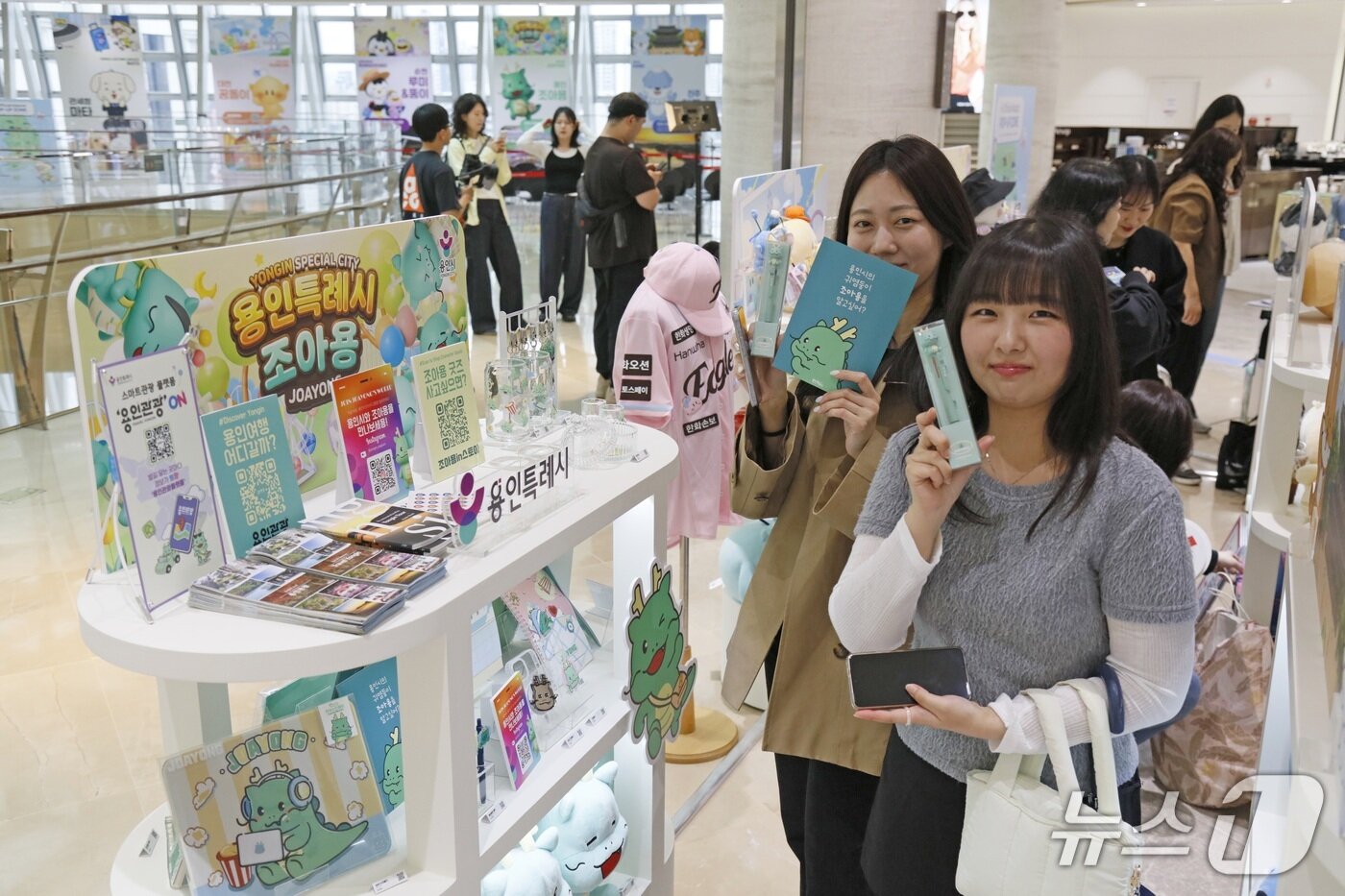 본문 이미지 - 외국 관광객이 서울 롯데면세점 월드타워점 ‘K-공공캐릭터 굿즈 팝업존’에서 용인시 대표 캐릭터 조아용 굿즈를 들고 기념촬영을 하고 있는 모습.(용인시 제공)