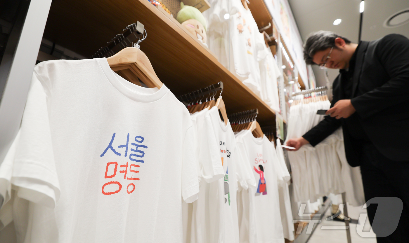 (서울=뉴스1) 이종수 인턴기자 = 유니클로 명동점이 문을 연 22일 서울 중구 매장 내 ‘UTme!(유티미)’ 존에서 한 시민이 명동 한정 디자인 티셔츠를 살펴보고 있다. 202 …