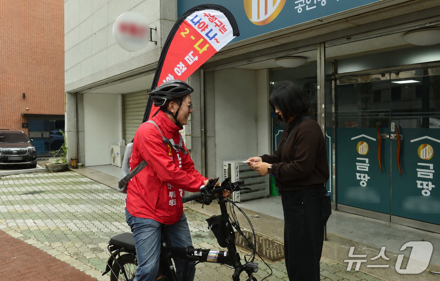 본문 이미지 - 22일 오전 대구 수성구 수성못에서 남정호 수성구의원(나선거구) 후보가 홍보 깃발을 등 뒤에 메고 자전거를 타며 선거유세를 하고 있다. 2026.5.22 ⓒ 뉴스1 이성덕 기자