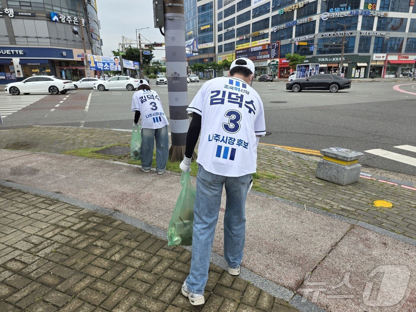본문 이미지 - 김덕수 조국혁신당 나주시장 후보 선거운동원들이 23일 나주혁신도시에서 유세를 하며 쓰레기봉투를 들고 쓰레기를 줍고 있다. ⓒ 뉴스1 서충섭 기자