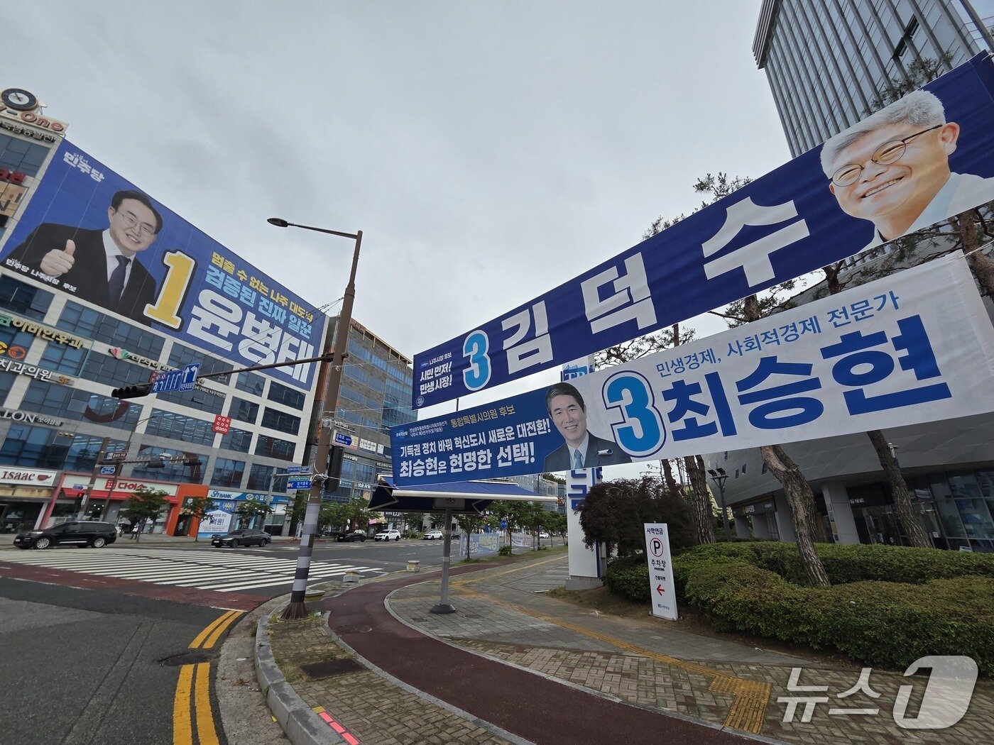 본문 이미지 - 6·3 지방선거 선거운동 첫 주말인 23일 전남 나주시장 선거 후보인 윤병태 더불어민주당 후보와 김덕수 조국혁신당 후보 현수막이 나주혁신도시 한전KDN 사거리 앞에 나란히 걸려 있다. 2026.5.23/뉴스1