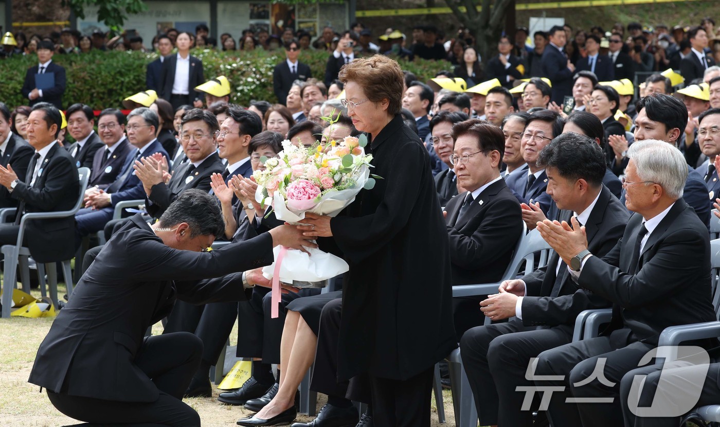 (김해=뉴스1) 이재명 기자 = 권양숙 여사가 23일 경남 김해 봉하마을에서 열린 고 노무현 전 대통령 서거 17주기 추도식에서 노무현재단 관계자로부터 꽃다발을 받고 있다. (청와 …