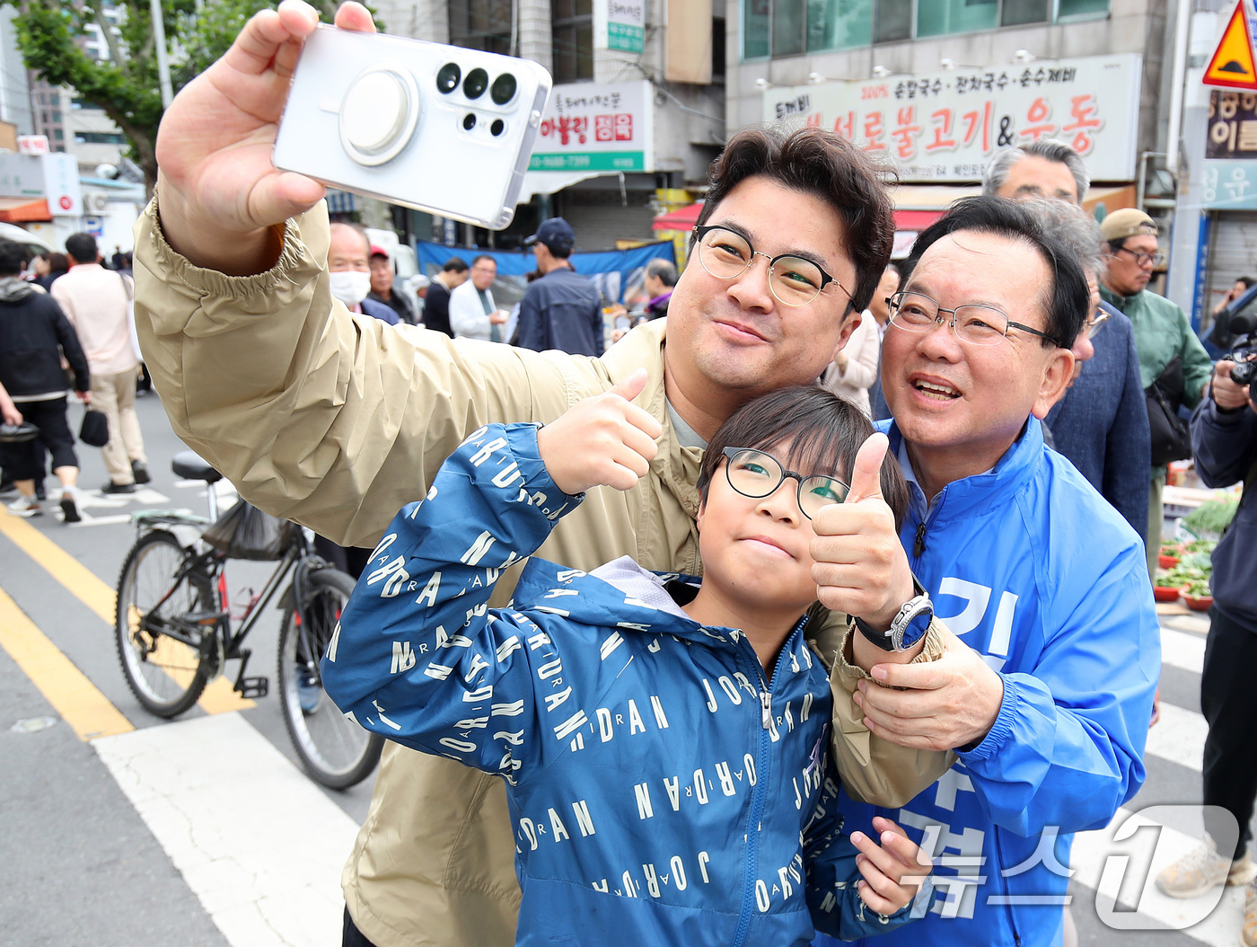 (대구=뉴스1) 공정식 기자 = 김부겸 더불어민주당 대구시장 후보가 23일 오전 대구 중구 달성공원 새벽시장을 찾아 시민과 인사 나눈 뒤 기념촬영을 하고 있다. 2026.5.23/ …