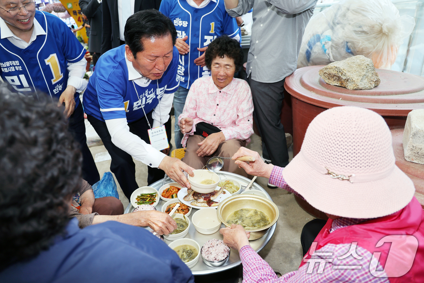 (광양=뉴스1) 황기선 기자 = 정청래 더불어민주당 대표가 24일 오후 전남 광양시 옥곡5일시장에서 상인들과 인사를 나누며 점심 음식을 맛보고 있다. 2026.5.24/뉴스1