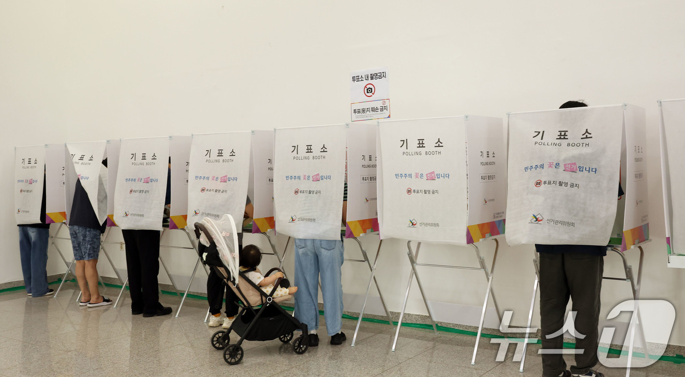 (광주=뉴스1) 박지현 기자 = 전국동시지방선거 사전투표 첫날인 29일 광주 북구 용봉동 사전투표소로 지정된 전남대학교 용지관컨벤션홀에서 유아차에 아이를 데리고 온 유권자가 투표를 …