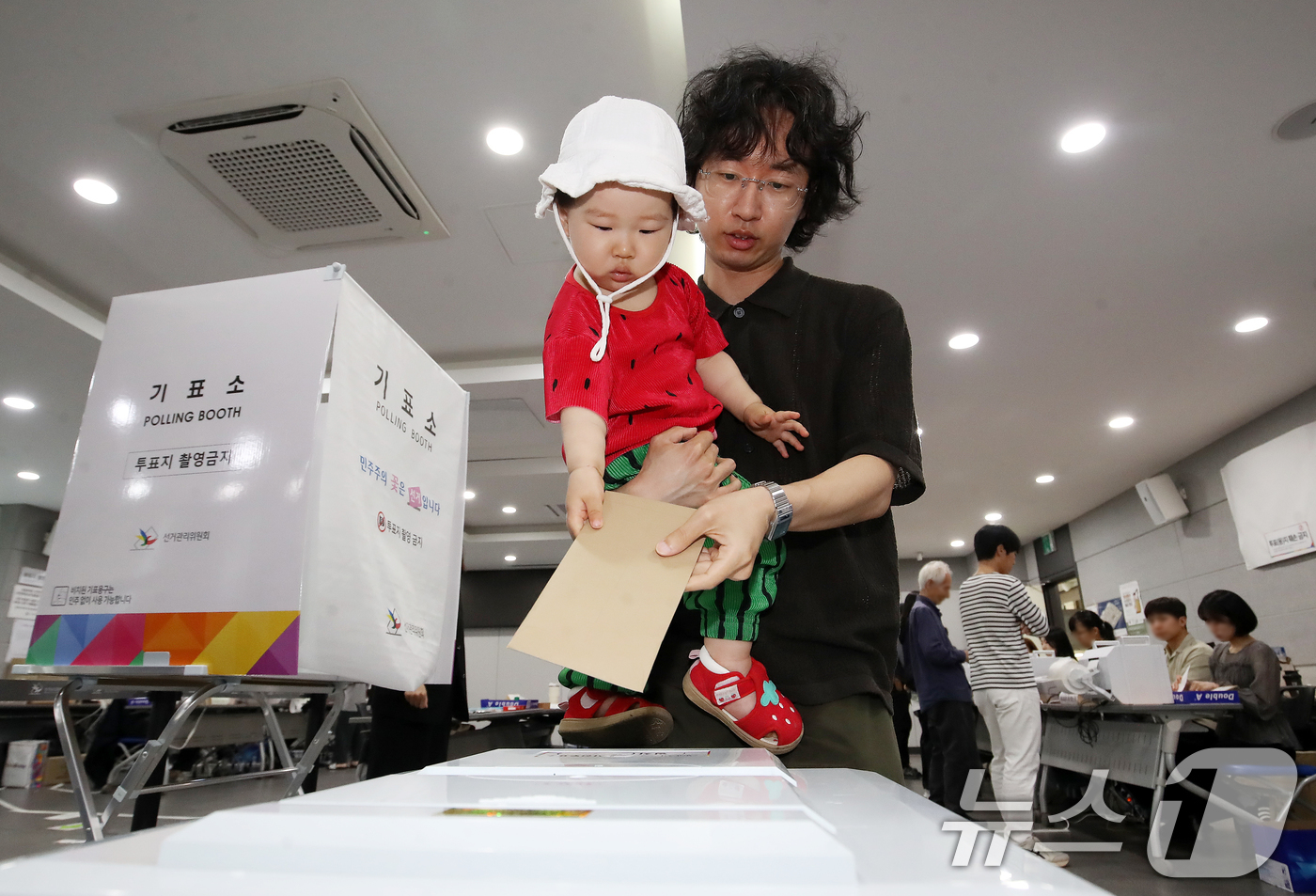(부산=뉴스1) 윤일지 기자 = 6·3 지방선거 및 국회의원 재보궐선거 사전투표 첫날인 29일 부산 연제구 연제구청에 마련된 사전투표소에서 한 유권자가 아이와 함께 소중한 한 표를 …