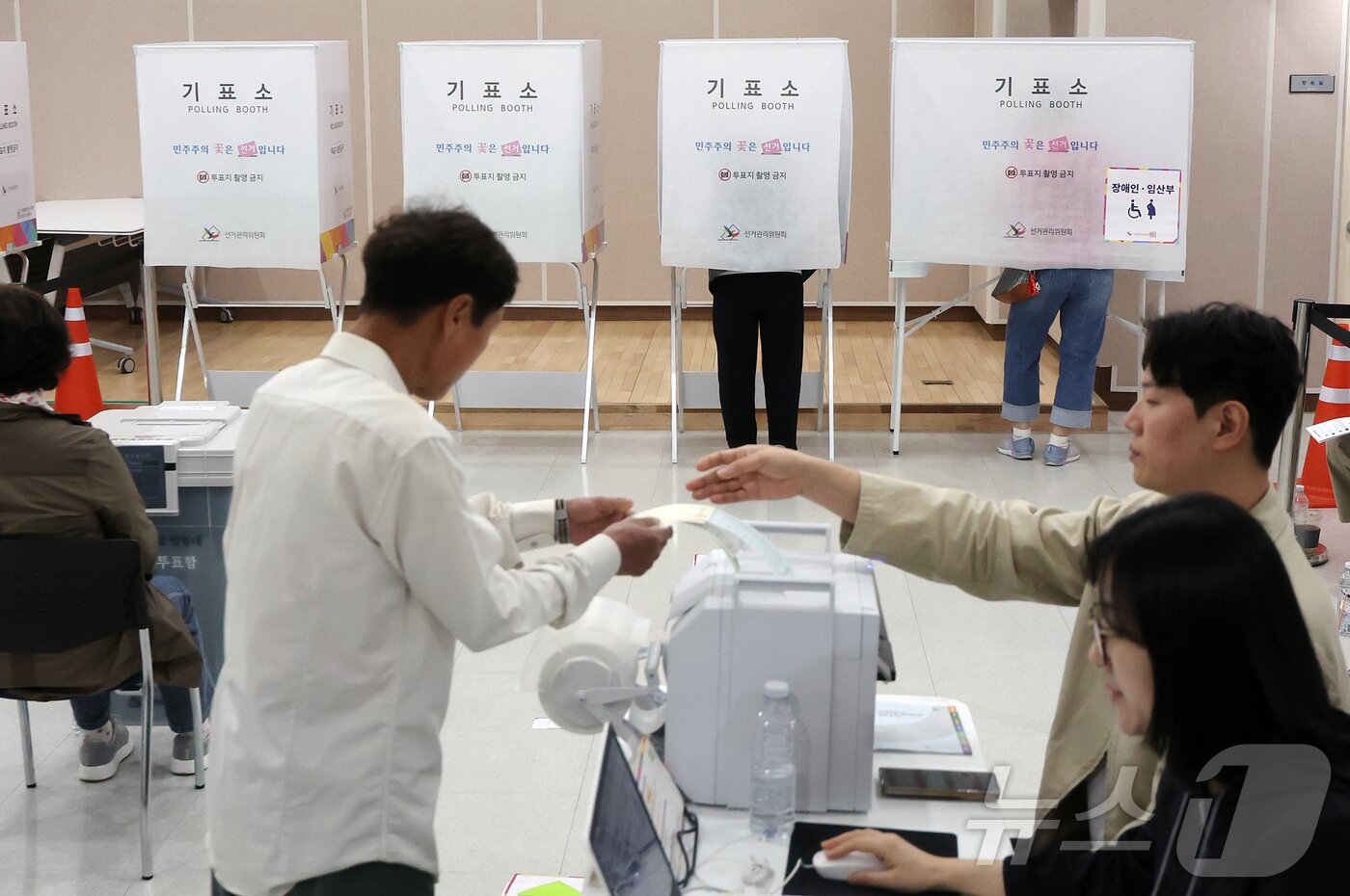 본문 이미지 - 제9회 전국동시지방선거 사전투표 둘째 날인 30일 서울 영등포구 신길4동주민센터에 마련된 사전투표소에서 유권자가 투표용지를 받고 있다. 2026.5.30 ⓒ 뉴스1 김진환 기자