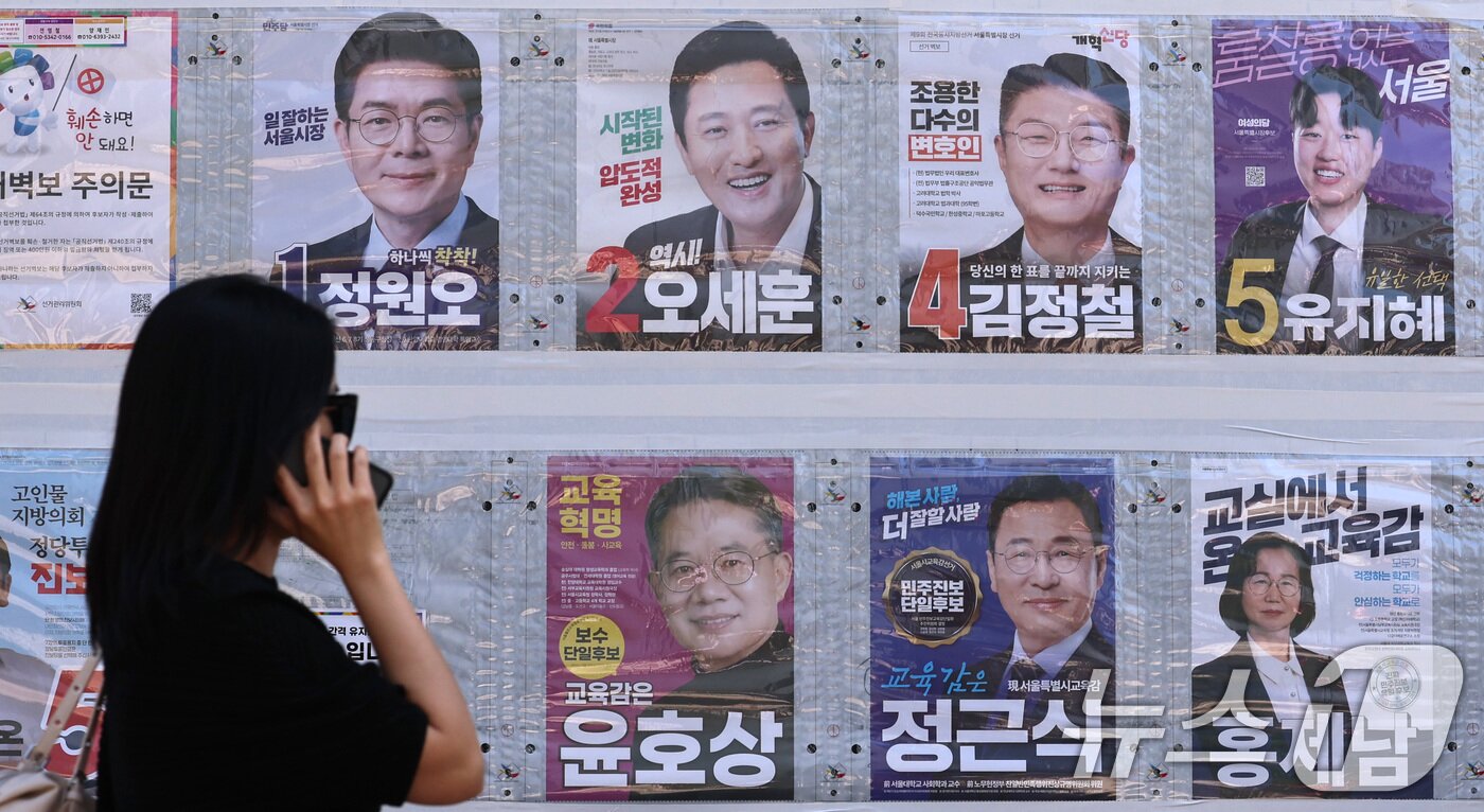 본문 이미지 - 제9회 전국동시지방선거일을 사흘 앞둔 31일 한 시민이 서울 중구 명동 일대에 붙은 선거벽보를 살피고 있다. 2026.5.31 ⓒ 뉴스1 구윤성 기자