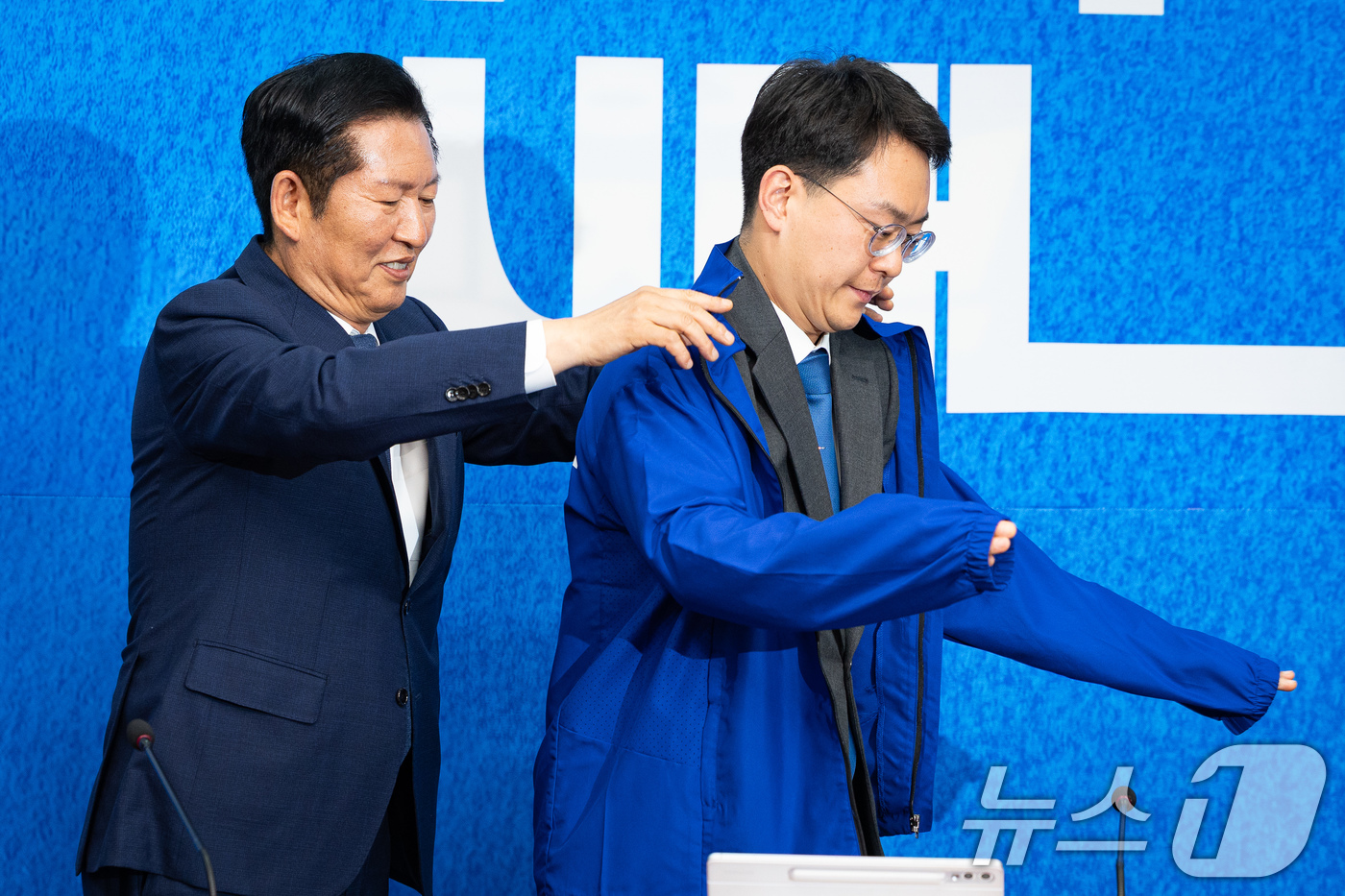 (서울=뉴스1) 유승관 기자 = 정청래 더불어민주당 대표가 6일 서울 여의도 국회에서 열린 발탁인재 환영식에서 발탁인재 2호 박지원 최고위원에게 당 점퍼를 입혀주고 있다.민주당 인 …