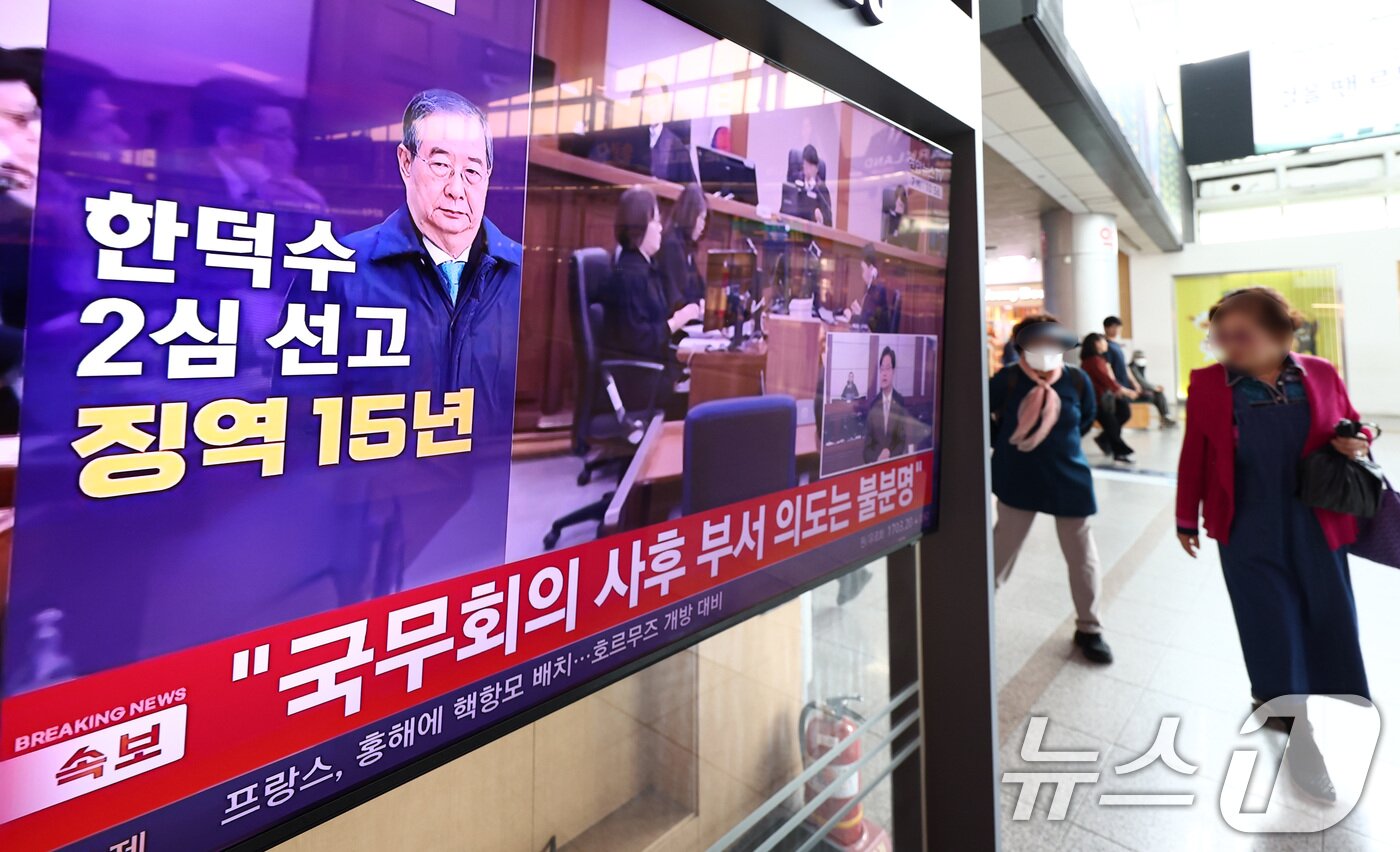 본문 이미지 - 서울 용산구 서울역 대합실에서 시민들이 12.3 비상계엄 사태와 관련해 내란 중요임무 종사 혐의를 받는 한덕수 전 국무총리의 항소심 선고 공판 관련 뉴스를 지켜보고 있다. 2026.5.7 ⓒ 뉴스1 최지환 기자