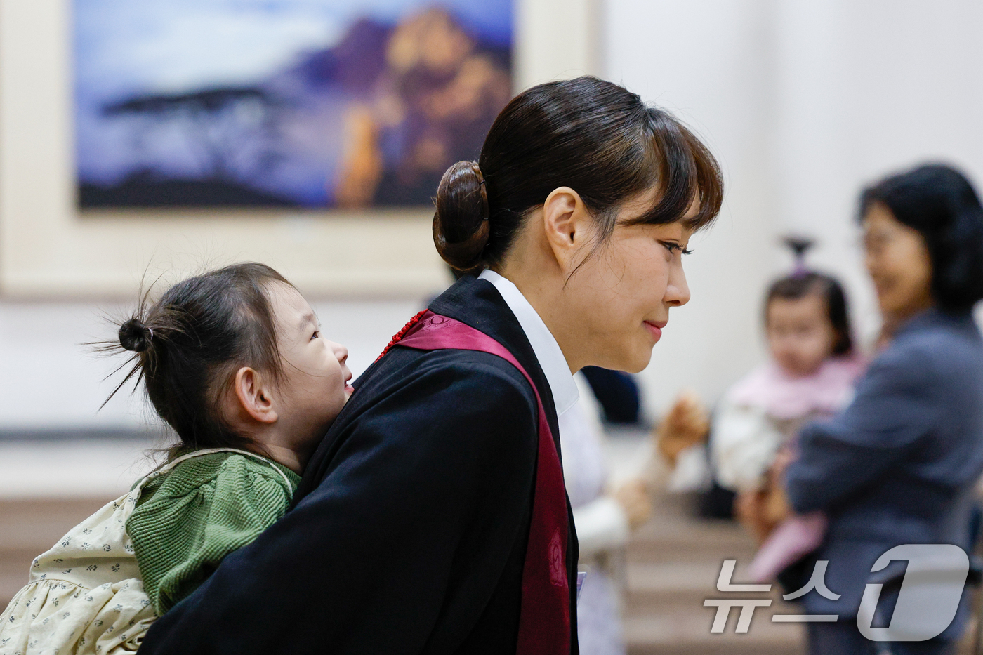 (과천=뉴스1) 안은나 기자 = 7일 경기 과천시 정부과천청사 법무부에서 2026 신임검사 임관식이 열린 가운데 한 신임검사가 딸을 등에 업고 있다. 2026.5.7/뉴스1