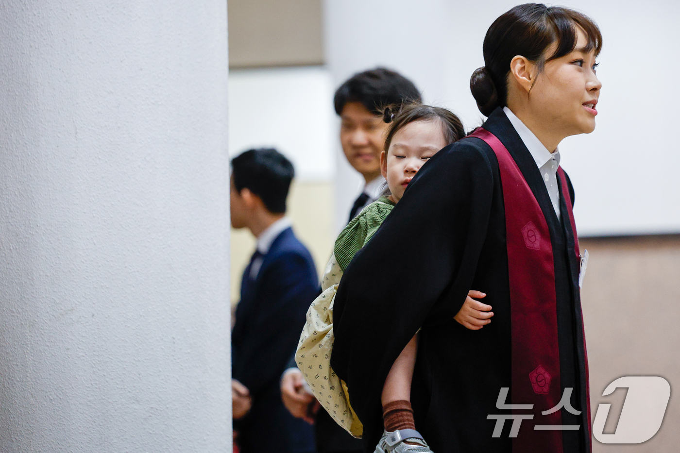 (과천=뉴스1) 안은나 기자 = 7일 경기 과천시 정부과천청사 법무부에서 2026 신임검사 임관식이 열린 가운데 한 신임검사가 딸을 등에 업고 있다. 2026.5.7/뉴스1