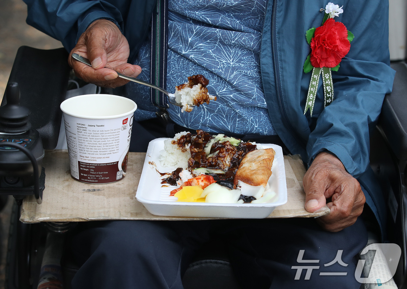 (대구=뉴스1) 공정식 기자 = 어버이날을 하루 앞둔 7일 대구 달서구 두류공원 사랑해밥차 무료급식소를 찾은 노인이 전동휠체어에서 점심을 먹고 있다. 가슴에는 급식소에서 봉사자들이 …
