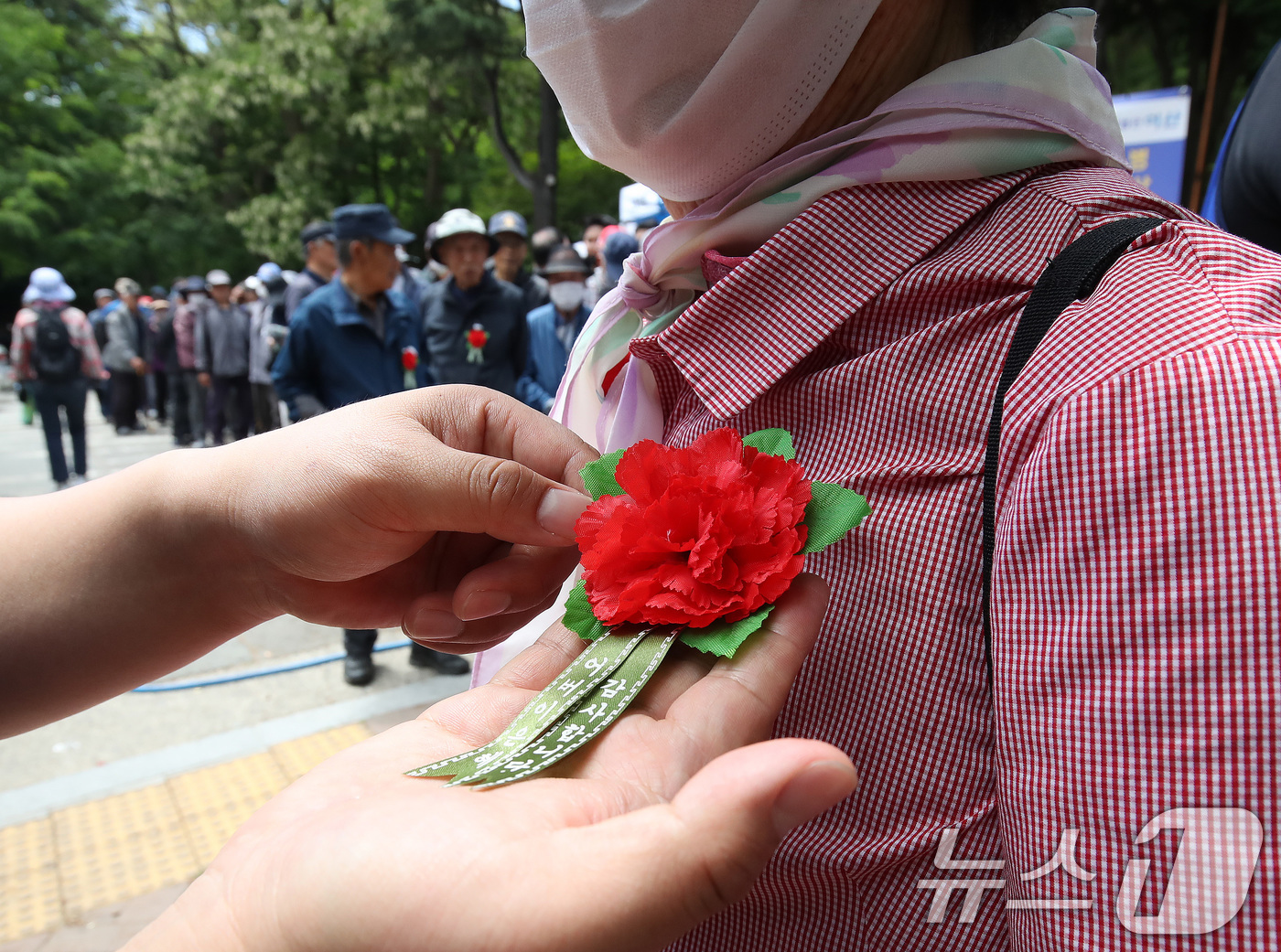 (대구=뉴스1) 공정식 기자 = 어버이날을 하루 앞둔 7일 대구 달서구 두류공원 사랑해밥차 무료급식소에서 봉사자들이 어르신에게 카네이션을 달아주고 있다. 2026.5.7/뉴스1