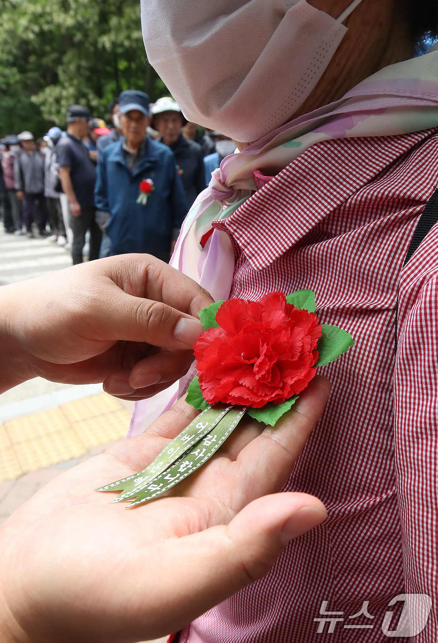 (대구=뉴스1) 공정식 기자 = 어버이날을 하루 앞둔 7일 대구 달서구 두류공원 사랑해밥차 무료급식소에서 봉사자들이 어르신에게 카네이션을 달아주고 있다. 2026.5.7/뉴스1