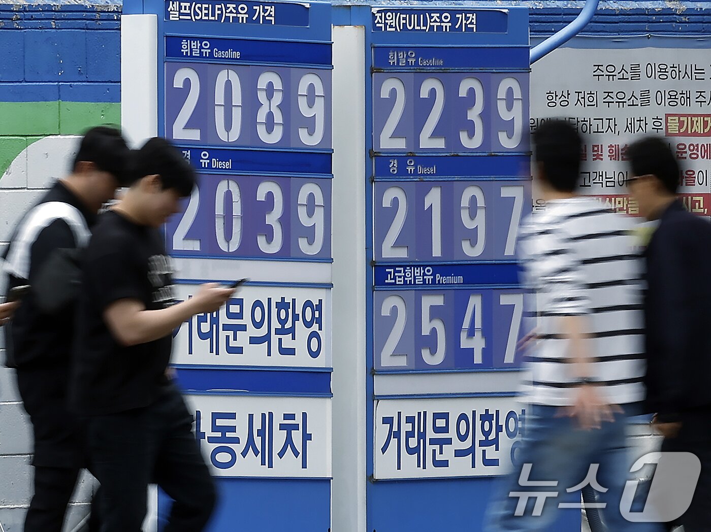 본문 이미지 - 5차 석유 최고가격제 시행을 하루 앞둔 7일 서울 시내 주유소에 설치된 휘발유, 경유 등 유가정보 안내판 앞으로 바이크와 차량을 탄 시민들이 지나가고 있다. 2026.5.7 ⓒ 뉴스1 박정호 기자
