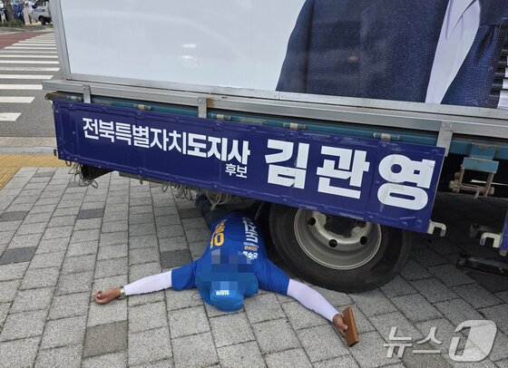 본문 이미지 - 1일 오전 8시 30분께 전북 전주시 효자동의 한 사거리에서 무소속 김관영 전북지사 후보 유세차 밑에 이원택 후보 선거운동원이 드러누운 모습.(독자 제공. 재판매 및 DB 금지) 2026.6.1 ⓒ 뉴스1 장수인 기자