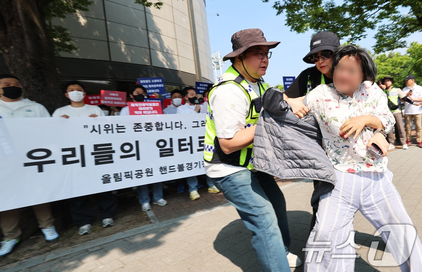 본문 이미지 - 11일 서울 송파구 올림픽공원 핸드볼경기장 앞에서 열린 핸드볼경기장 입주 체육단체 직원들의 업무 정상화 호소문 발표 기자회견 도중 한 여성이 기자회견을 가로막으며 항의하고 있다. 2026.6.11 ⓒ 뉴스1 오대일 기자
