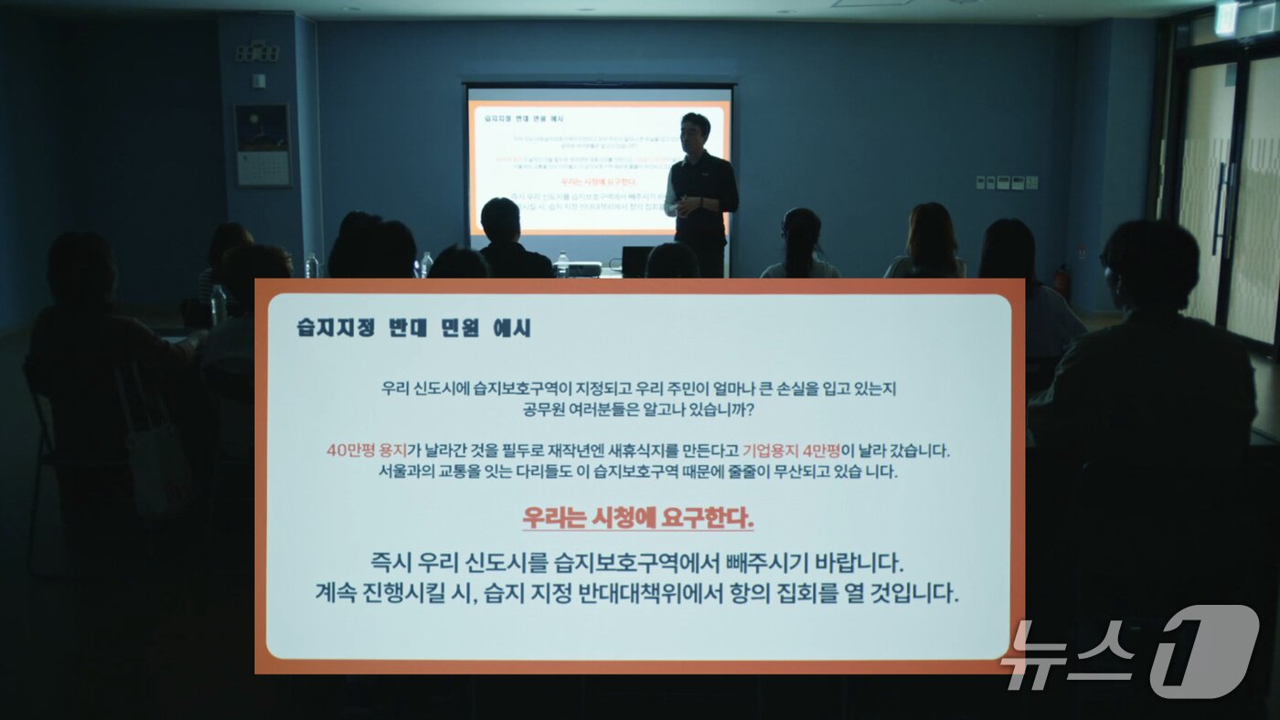 본문 이미지 - 영화 '신도시케이'에서 아파트 입주자대표가 시청에 '습지 보호구역 지정 반대 민원'을 넣을 것을 주민들에게 요구하는 장면(환경재단 제공) ⓒ 뉴스1