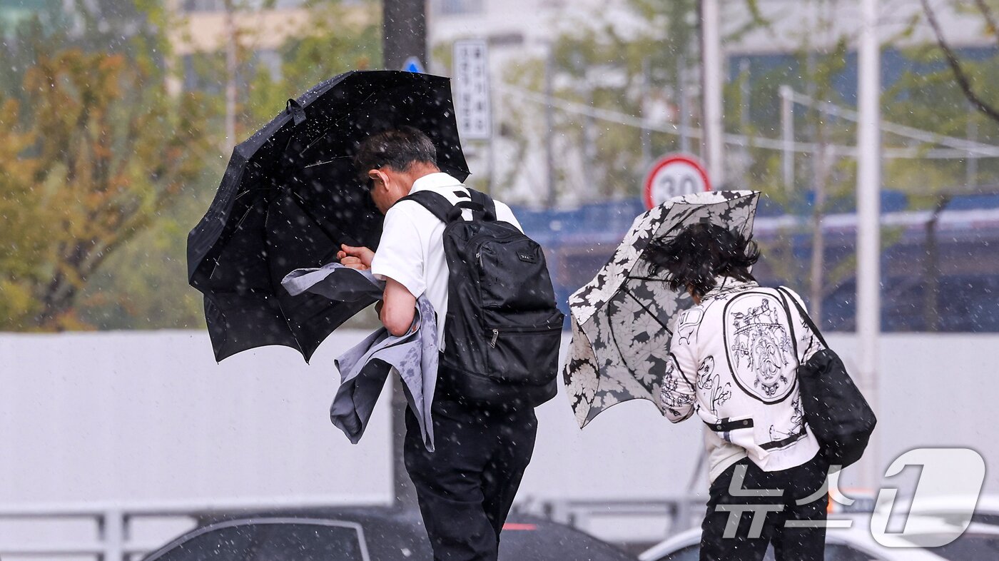 본문 이미지 - 돌풍과 벼락을 동반한 소나기가 내린 14일 서울 종로구 광화문광장에서 시민들이 우산을 쓰고 발걸음을 옮기고 있다. 2026.6.14 ⓒ 뉴스1 이호윤 기자