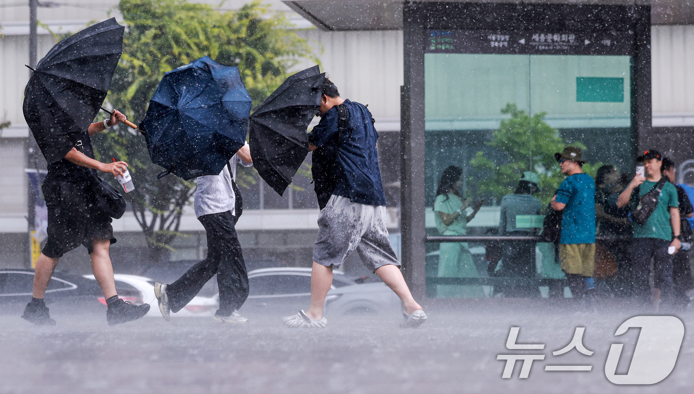 (서울=뉴스1) 이호윤 기자 = 돌풍과 벼락을 동반한 소나기가 내린 14일 서울 종로구 광화문광장에서 시민들이 우산을 쓰고 발걸음을 옮기고 있다. 2026.6.14/뉴스1