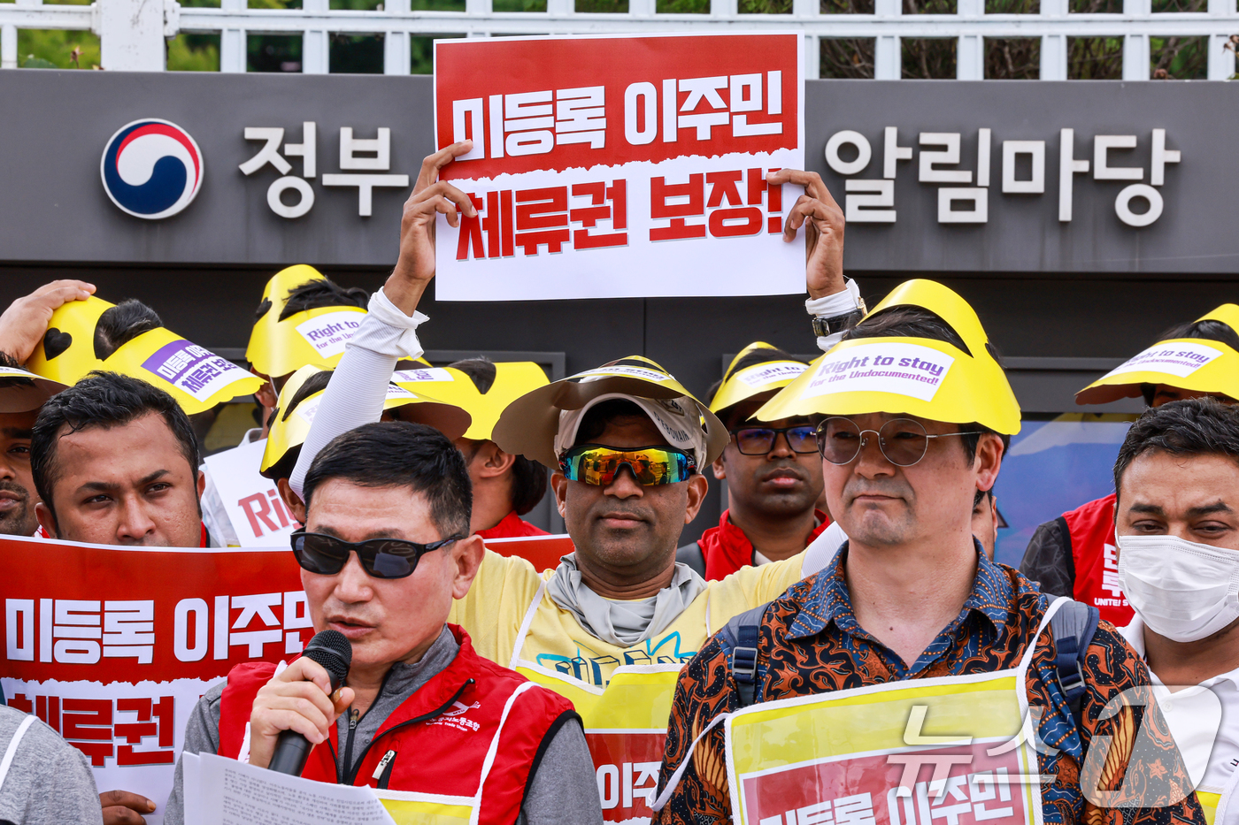(서울=뉴스1) 이호윤 기자 = 14일 서울 정부서울청사 앞에서 열린 미등록 이주민 체류권 보장 촉구 오체투지 행진 기자회견에서 참가자들이 피켓을 들고 있다. 2026.6.14/뉴 …
