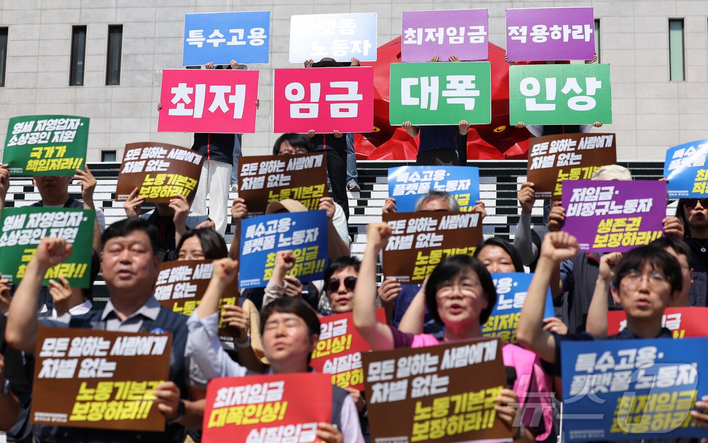 본문 이미지 - 한국노총과 민주노총 관계자들이 15일 서울 종로구 세종문화회관 앞 계단에서 열린 2027년 적용 최저임금 노동계 요구안 발표 기자회견에서 구호를 외치고 있다. 2026.6.15 ⓒ 뉴스1 김성진 기자