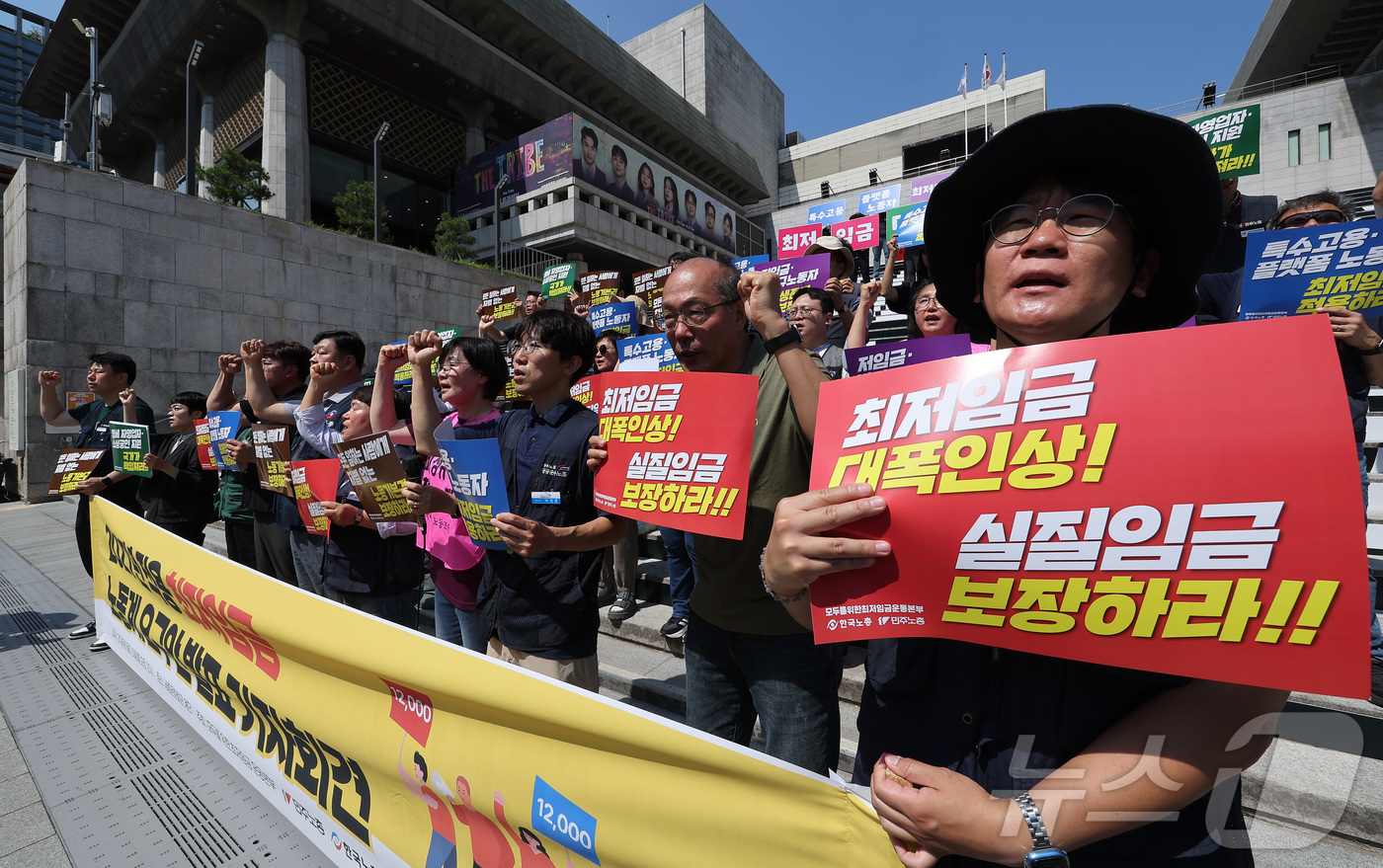 (서울=뉴스1) 김성진 기자 = 한국노총과 민주노총 관계자들이 15일 서울 종로구 세종문화회관 앞 계단에서 열린 2027년 적용 최저임금 노동계 요구안 발표 기자회견에서 구호를 외 …