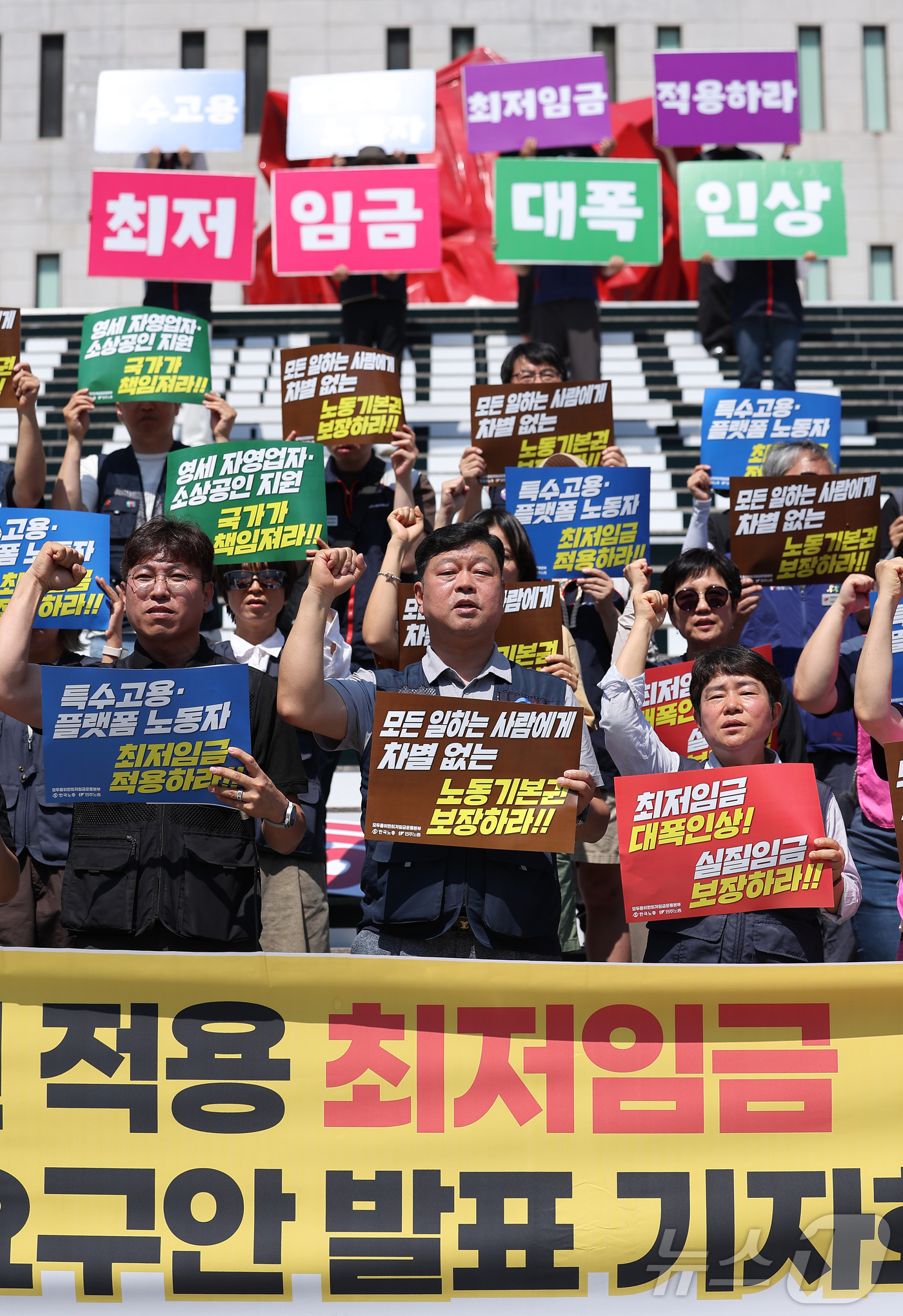 (서울=뉴스1) 김성진 기자 = 한국노총과 민주노총 관계자들이 15일 서울 종로구 세종문화회관 앞 계단에서 열린 2027년 적용 최저임금 노동계 요구안 발표 기자회견에서 구호를 외 …