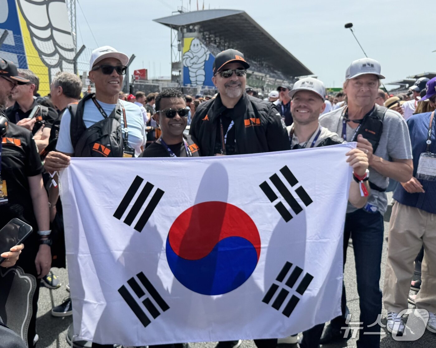 본문 이미지 - 13일 프랑스 르망 라 사르트 서킷에서 르망24시간 개막 전 열린 '그리드 워크' 행사에서 제네시스 해외 법인 관계자들이 GMR-001 차량 앞에서 태극기를 들고 사진을 촬영하는 모습 2026.6.16/뉴스1 ⓒ 뉴스1 박종홍 기자