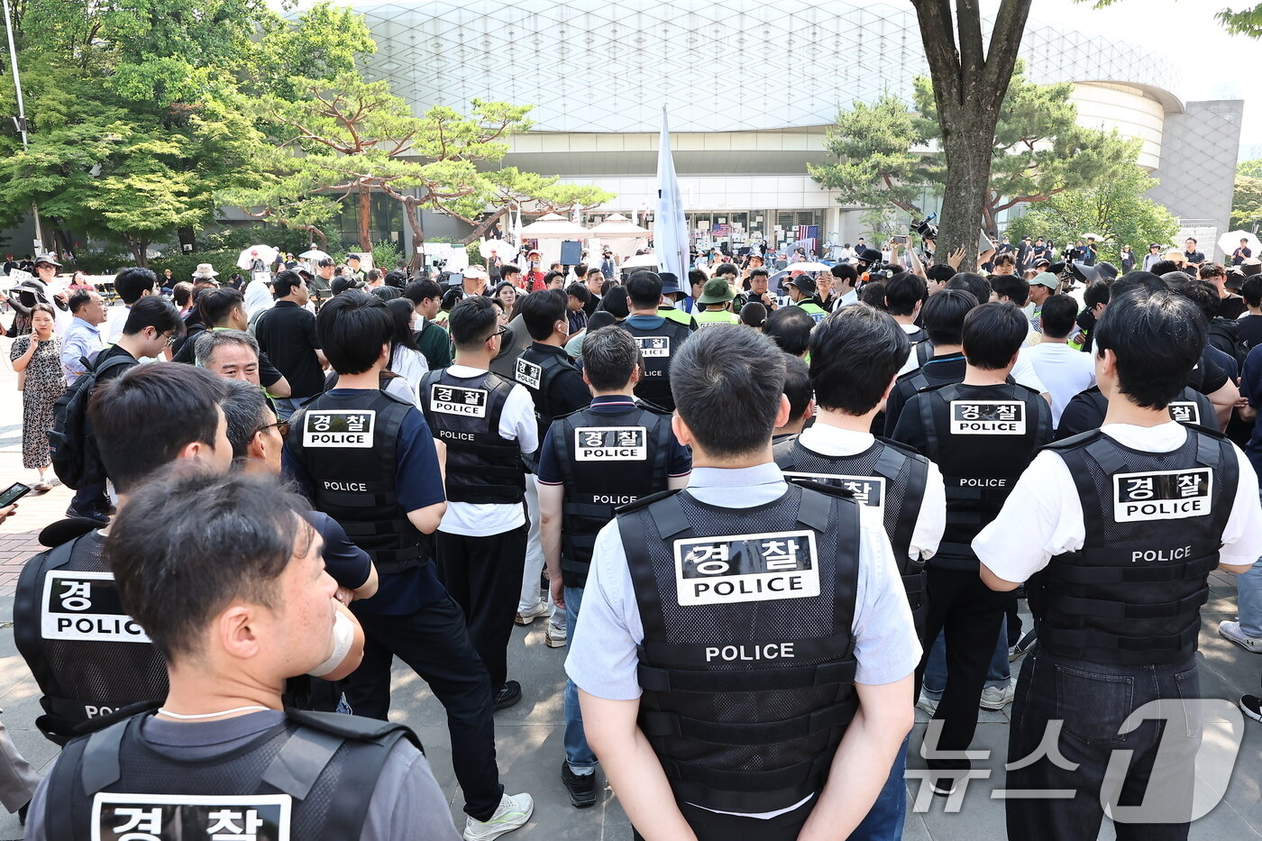 본문 이미지 - 6·3 지방선거 '투표용지 부족 사태'로 12일째 잠실 개표소 봉쇄 시위가 이어지고 있는 16일 경찰과 대한체육회 등관계자들이 서울 송파구 올림픽공원 핸드볼경기장 진입을 시도하다 시위대와 대치하고 있다. 2026.6.16 ⓒ 뉴스1 김도우 기자