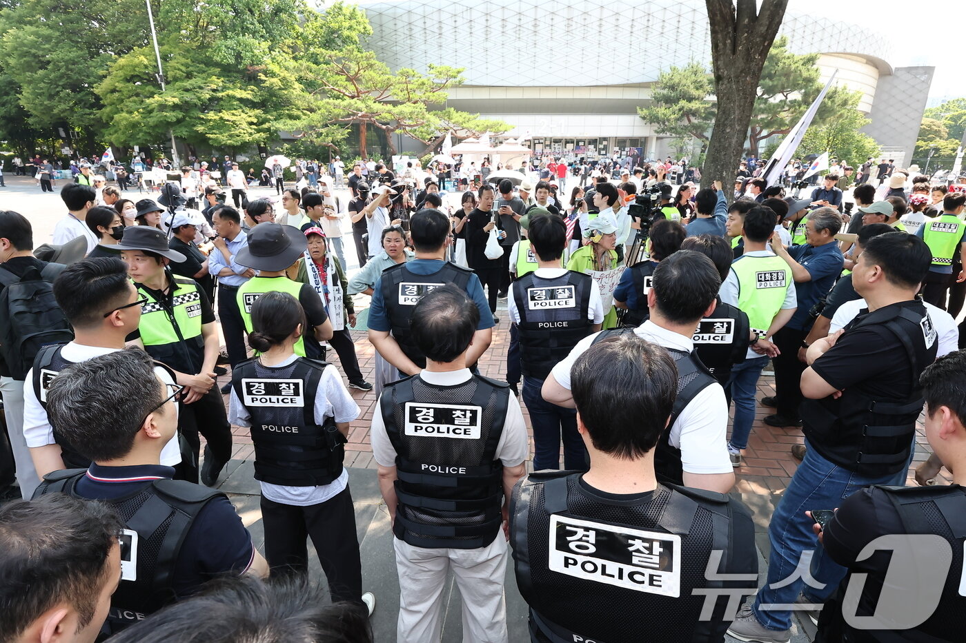 본문 이미지 - 6·3 지방선거 '투표용지 부족 사태'로 12일째 잠실 개표소 봉쇄 시위가 이어지고 있는 16일 경찰과 대한체육회 등관계자들이 서울 송파구 올림픽공원 핸드볼경기장 진입을 시도하다 시위대와 대치하고 있다. 2026.6.16 ⓒ 뉴스1 김도우 기자