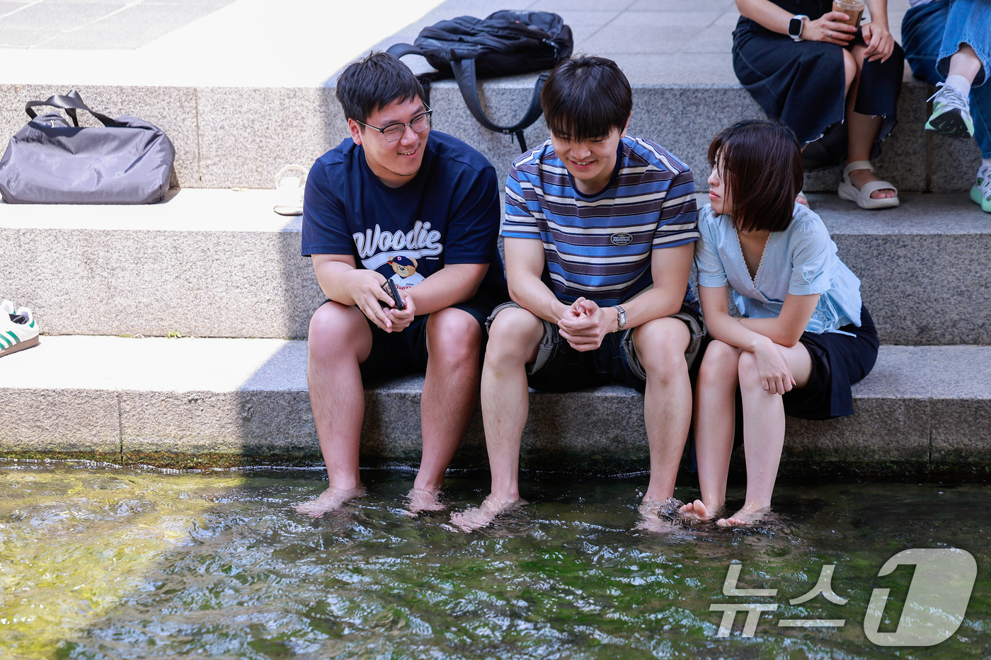 (서울=뉴스1) 안은나 기자 = 서울 낮 최고기온 33도로 무더운 날씨가 이어진 16일 오후 서울 종로구 청계천을 찾은 시민들이 발을 담그며 대화하고 있다. 2026.6.16/뉴스 …
