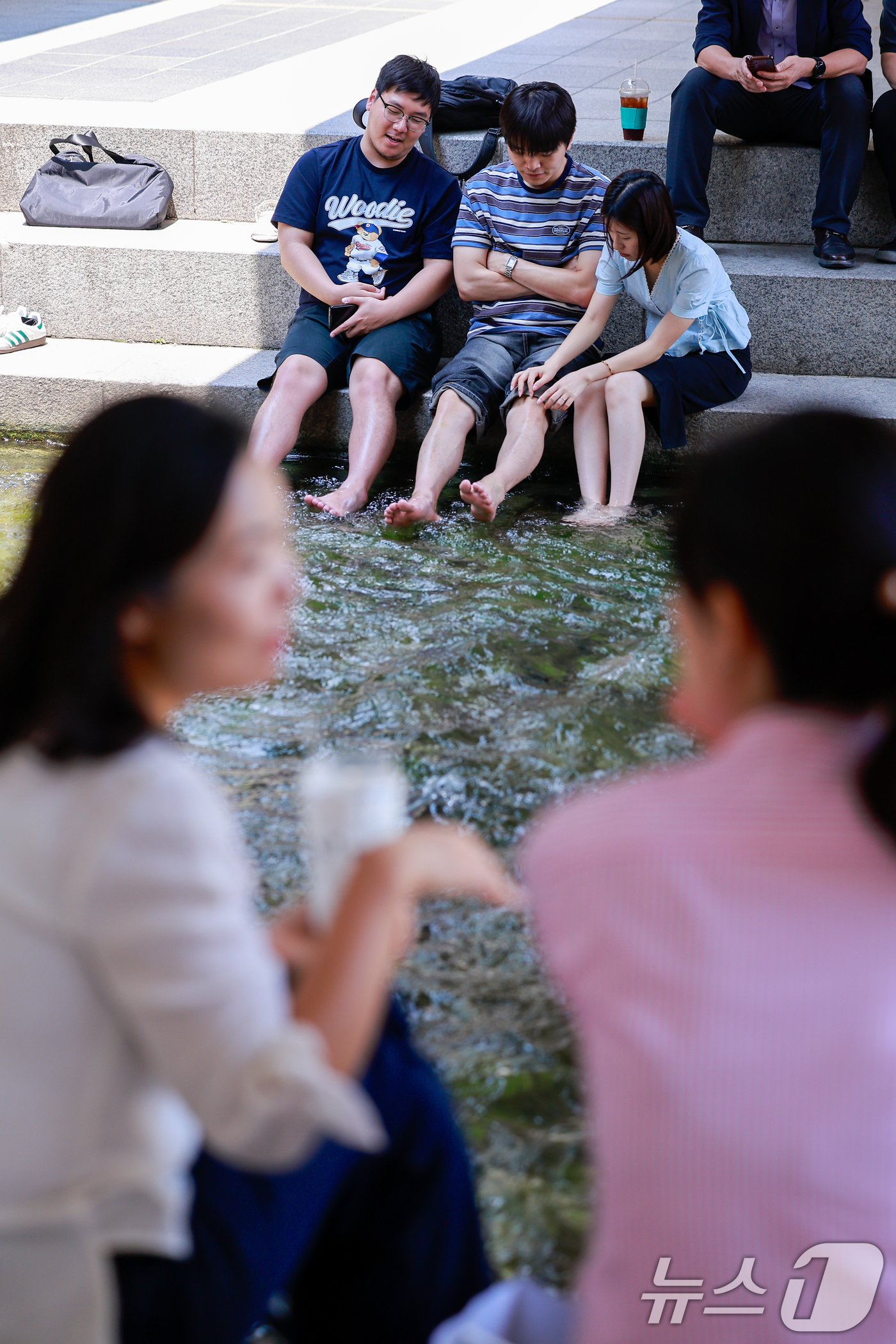 (서울=뉴스1) 안은나 기자 = 서울 낮 최고기온 33도로 무더운 날씨가 이어진 16일 오후 서울 종로구 청계천을 찾은 시민들이 발을 담그며 대화하고 있다. 2026.6.16/뉴스 …