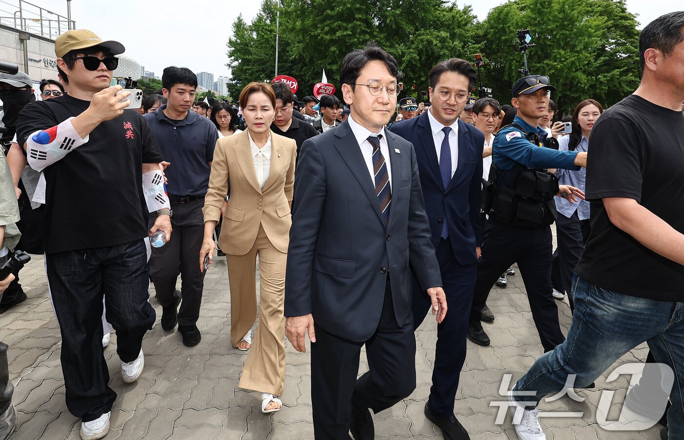 본문 이미지 - 임오경, 천준호, 전용기 더불어민주당 의원이 17일 서울 송파구 올림픽공원 핸드볼경기장 앞에서 투표용지 부족 사태를 규탄하는 시민들에게 항의를 받고 있다. 2026.6.17 ⓒ 뉴스1 김도우 기자
