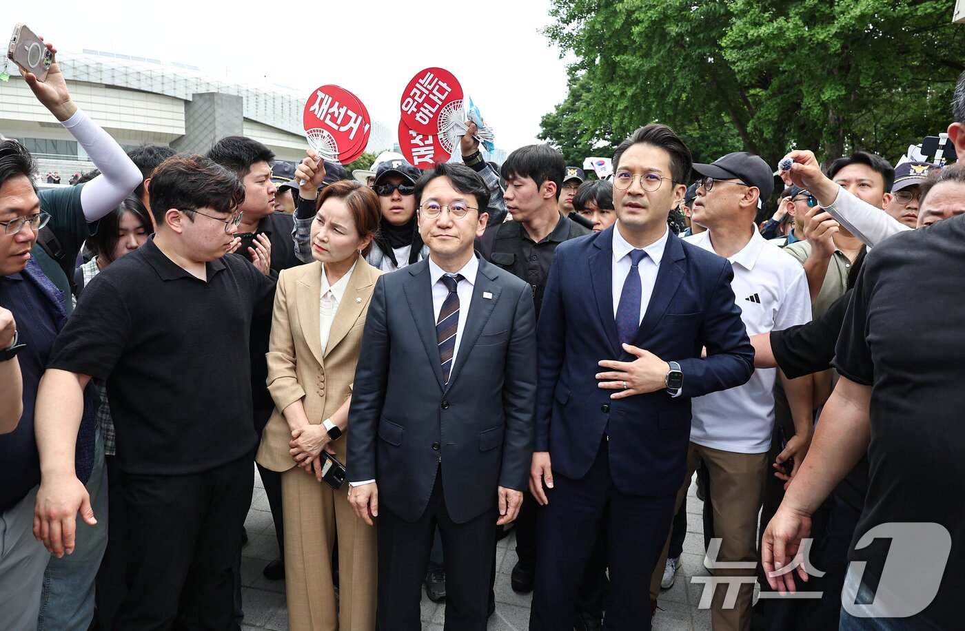 본문 이미지 - 임오경, 천준호, 전용기 더불어민주당 의원이 17일 서울 송파구 올림픽공원 핸드볼경기장 앞에서 투표용지 부족 사태를 규탄하는 시민들에게 항의를 받으며 이동하고 있다. 2026.6.17 ⓒ 뉴스1 김도우 기자