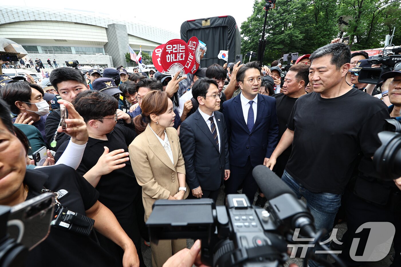 본문 이미지 - 임오경, 전용기, 천준호 더불어민주당 의원이 17일 서울 송파구 올림픽공원 핸드볼경기장 앞에서 투표용지 부족 사태를 규탄하는 시민들에게 항의를 받으며 이동하고 있다. 2026.6.17 ⓒ 뉴스1 김도우 기자