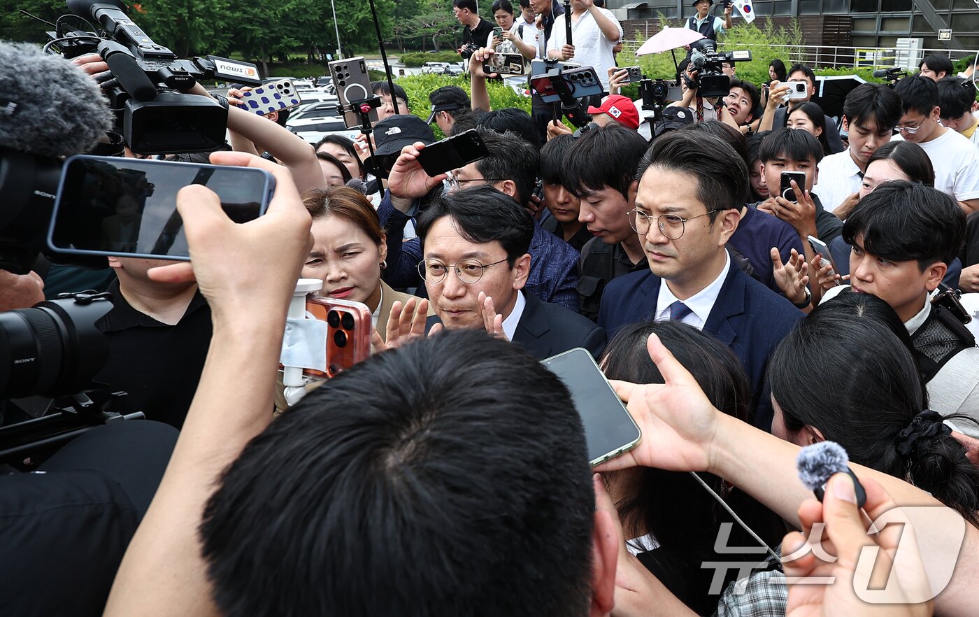 본문 이미지 - 임오경, 전용기, 천준호 더불어민주당 의원이 17일 서울 송파구 올림픽공원 핸드볼경기장 앞에서 투표용지 부족 사태를 규탄하는 시민들에게 항의를 받으며 이동하고 있다. 2026.6.17 ⓒ 뉴스1 김도우 기자
