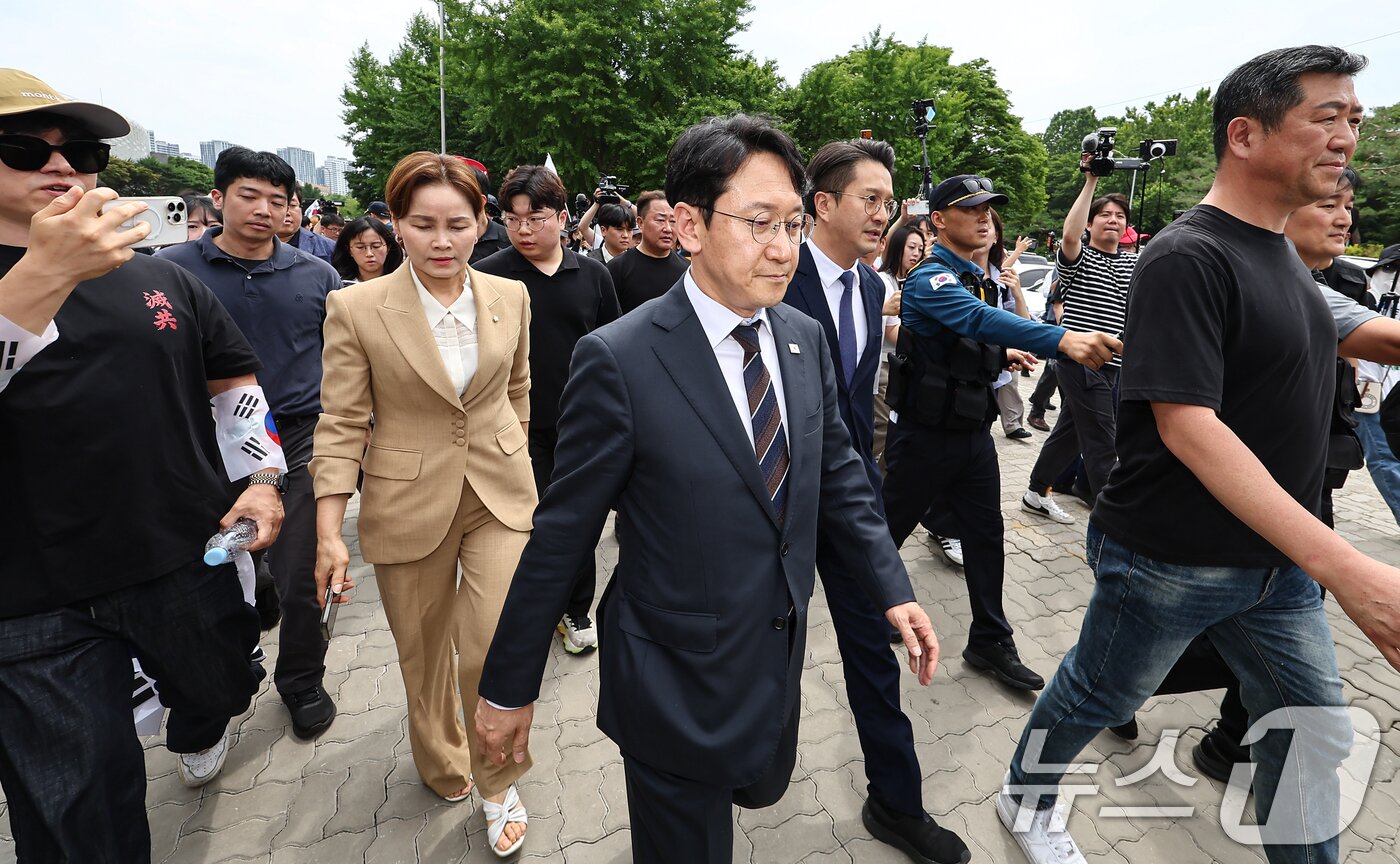 본문 이미지 - 임오경, 전용기, 천준호 더불어민주당 의원이 17일 서울 송파구 올림픽공원 핸드볼경기장 앞에서 투표용지 부족 사태를 규탄하는 시민들에게 항의를 받으며 이동하고 있다. 2026.6.17 ⓒ 뉴스1 김도우 기자